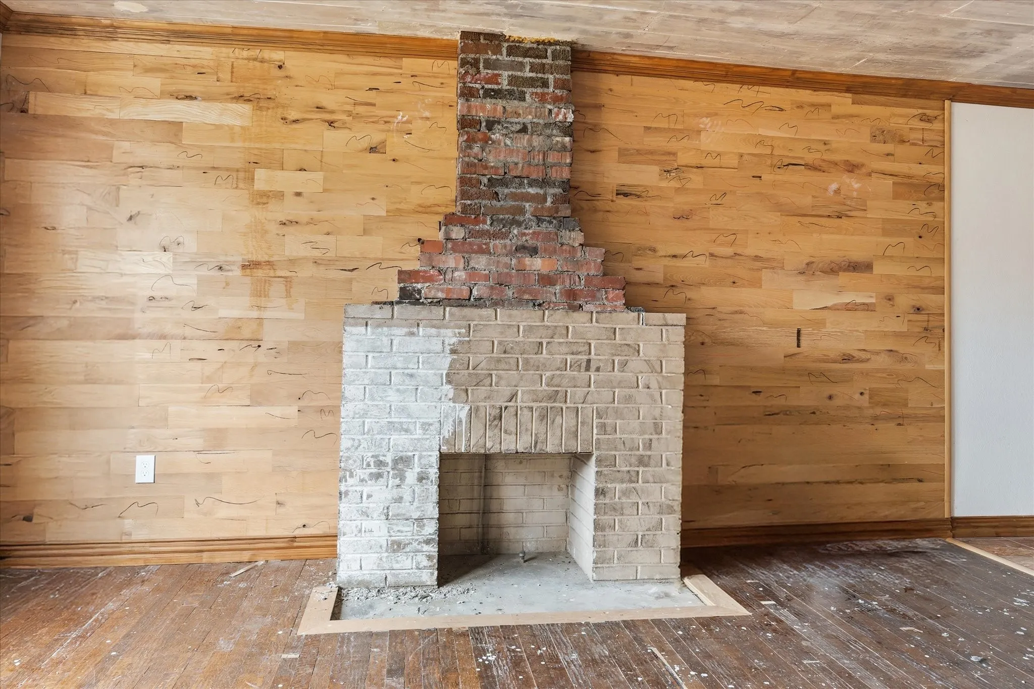 Brick fireplace with a partially painted hearth and exposed brick chimney