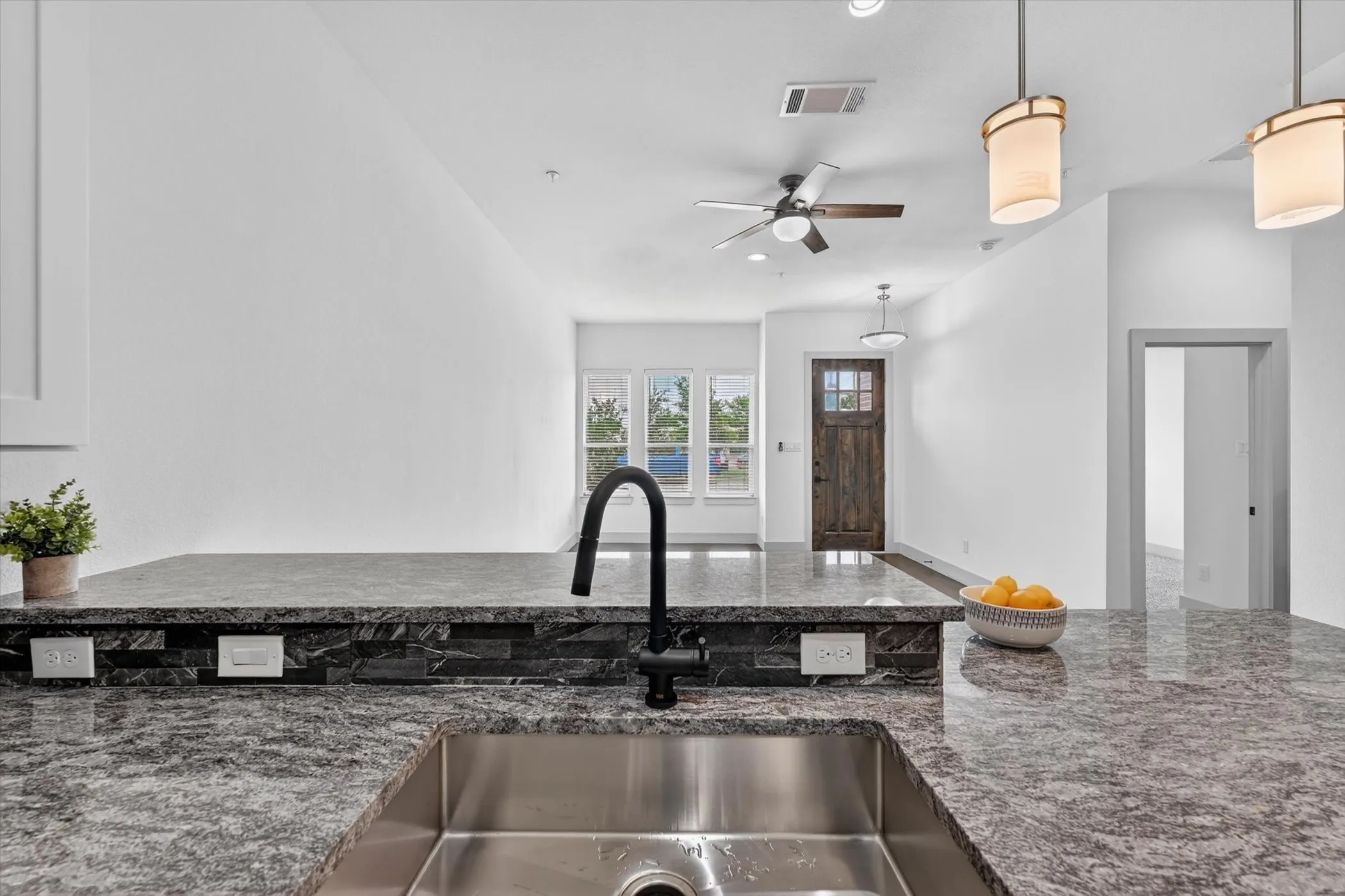 Kitchen island featuring a stainless steel sink, black gooseneck faucet, and granite countertops