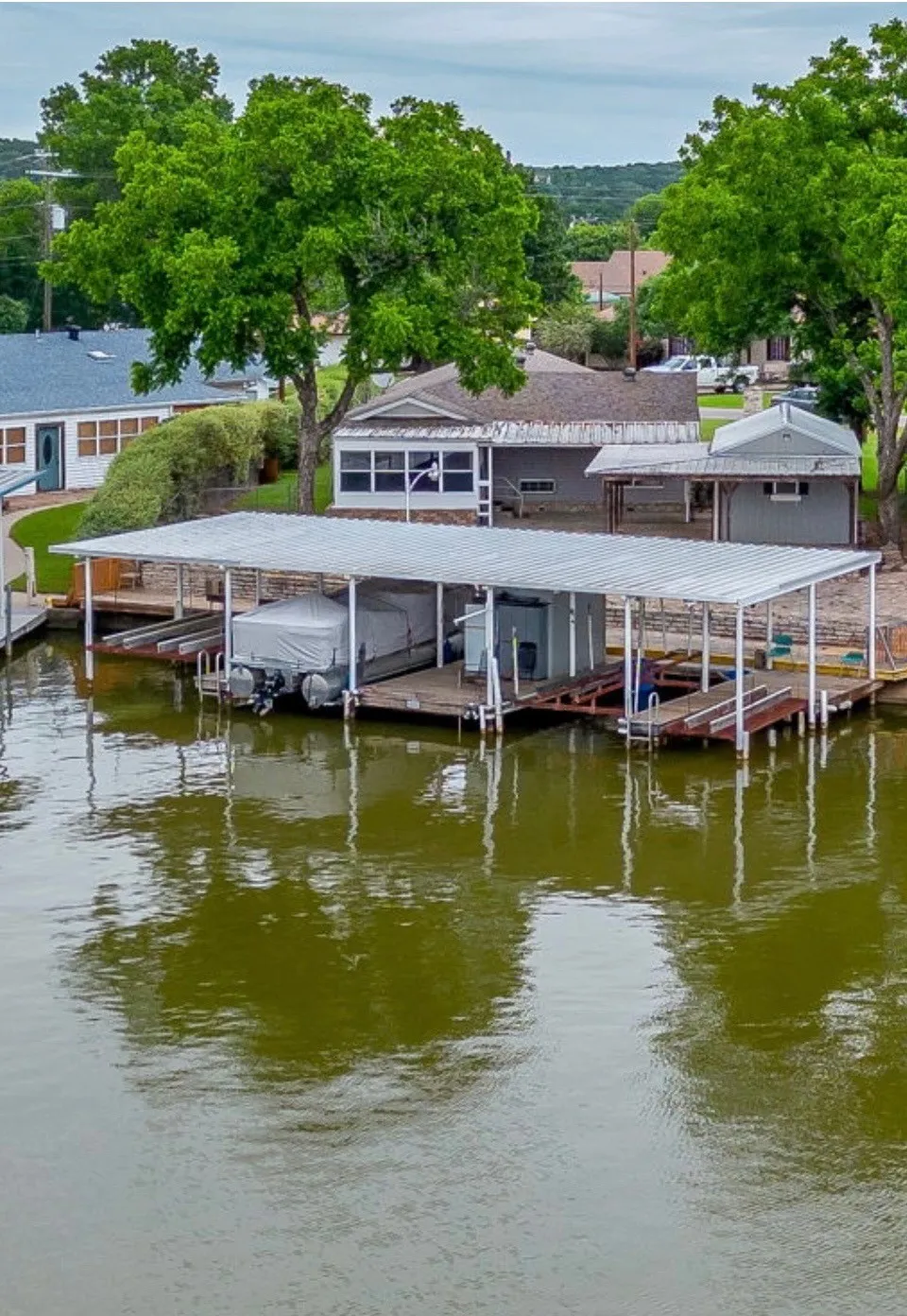 Waterfront property featuring a covered boat dock with multiple slips, a metal roof, and wooden decking