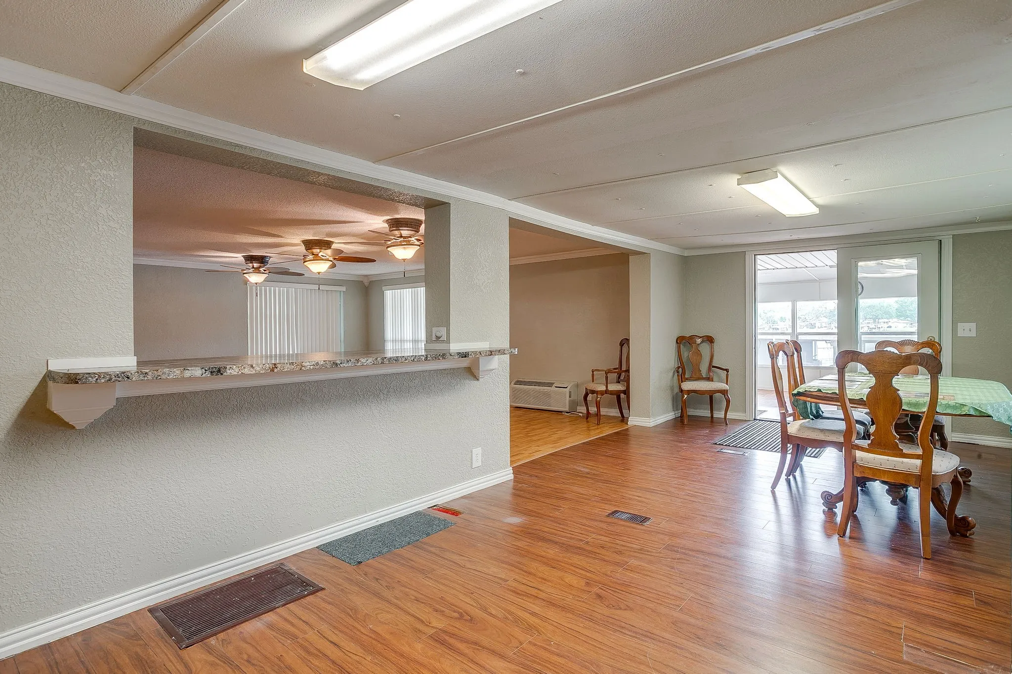 Open-concept living area featuring wood-finish flooring, a pass-through counter with a stone-finish surface, and recessed lighting