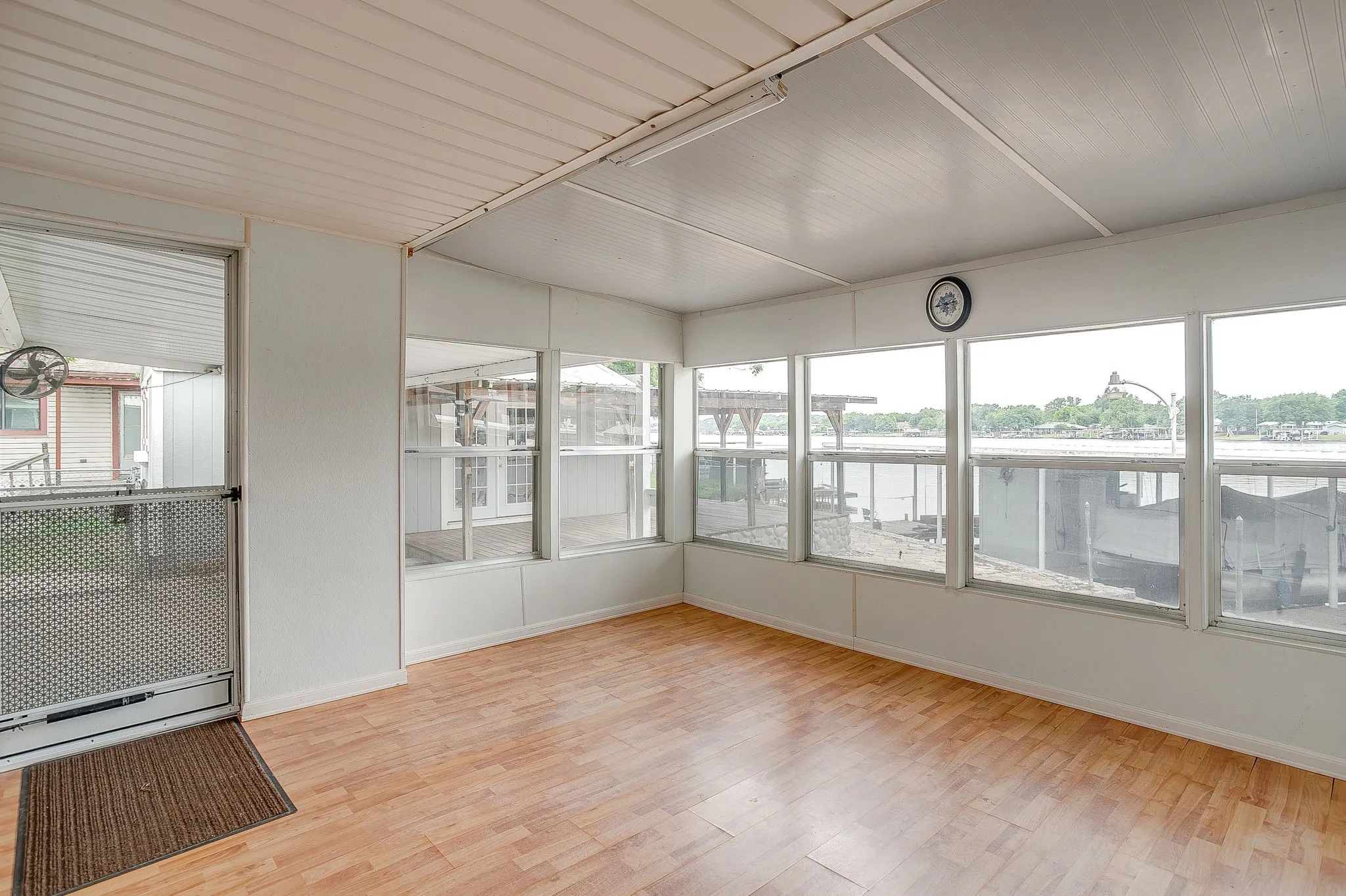 Enclosed sunroom featuring wood-finish flooring and multiple large windows overlooking a body of water