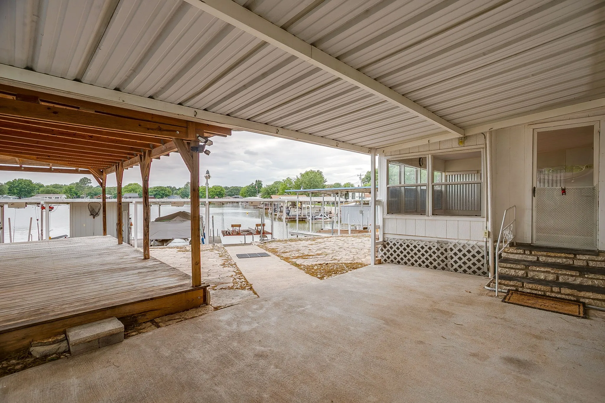 Covered patio area featuring a concrete slab and wood deck overlooking a body of water