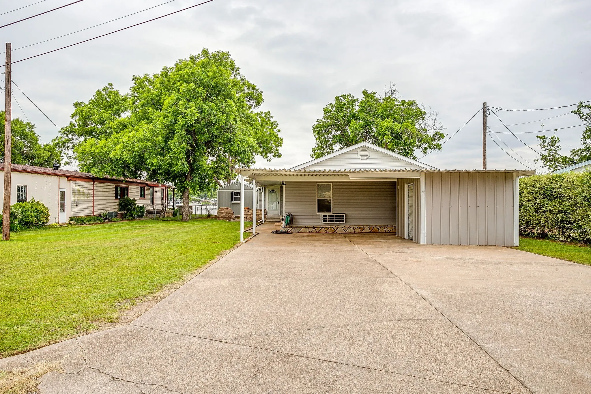 Single-story residence featuring siding exterior, an attached carport, and a concrete driveway