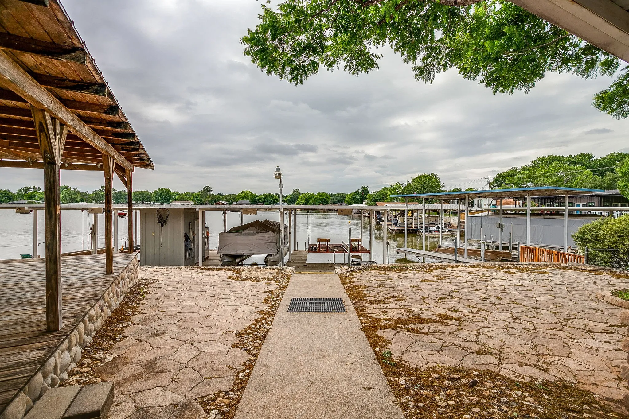 Waterfront property featuring a covered boat dock, direct water access, a flagstone patio, and a concrete pathway