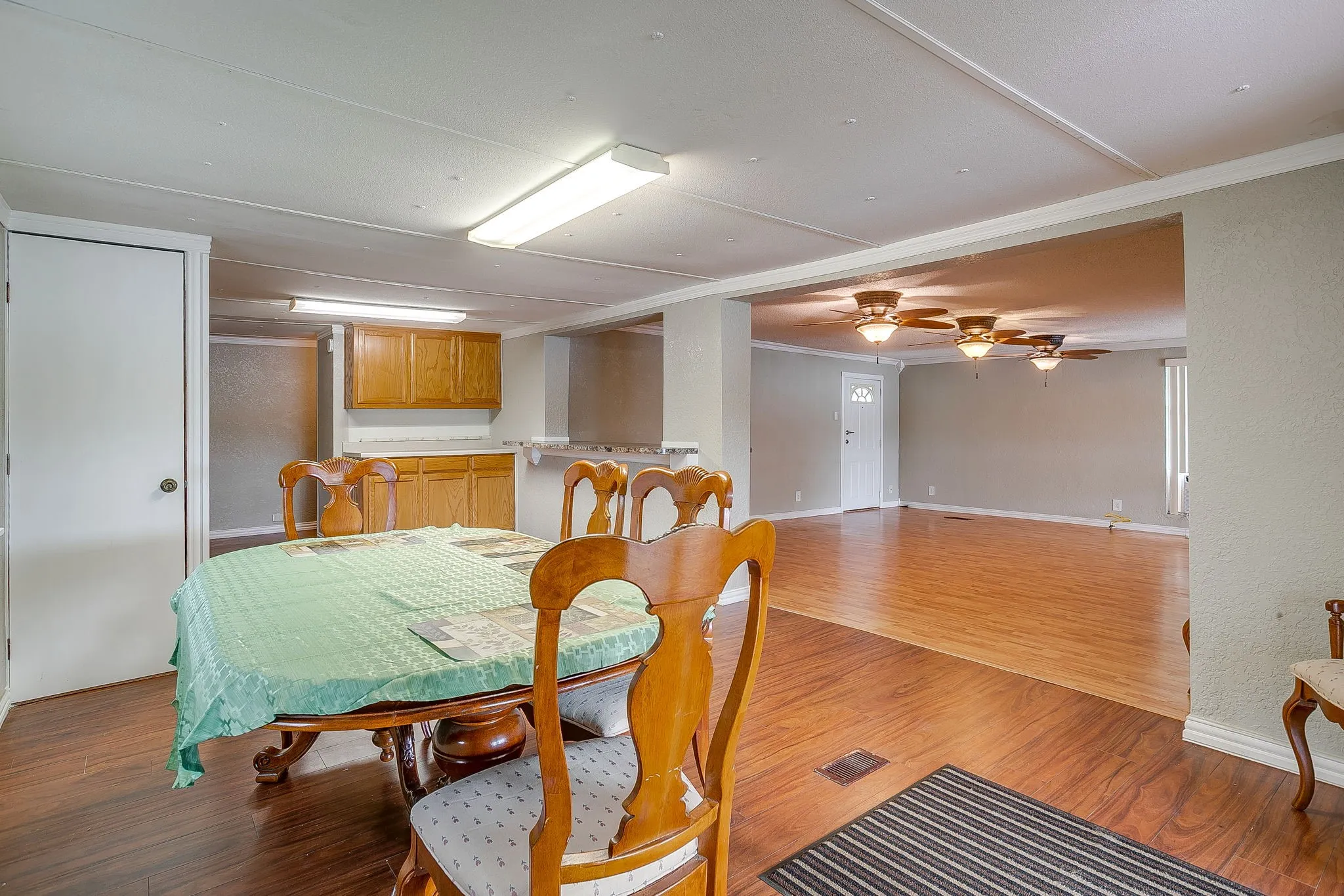 Open-concept interior featuring wood-finish flooring, a neutral color palette, and multiple ceiling fans