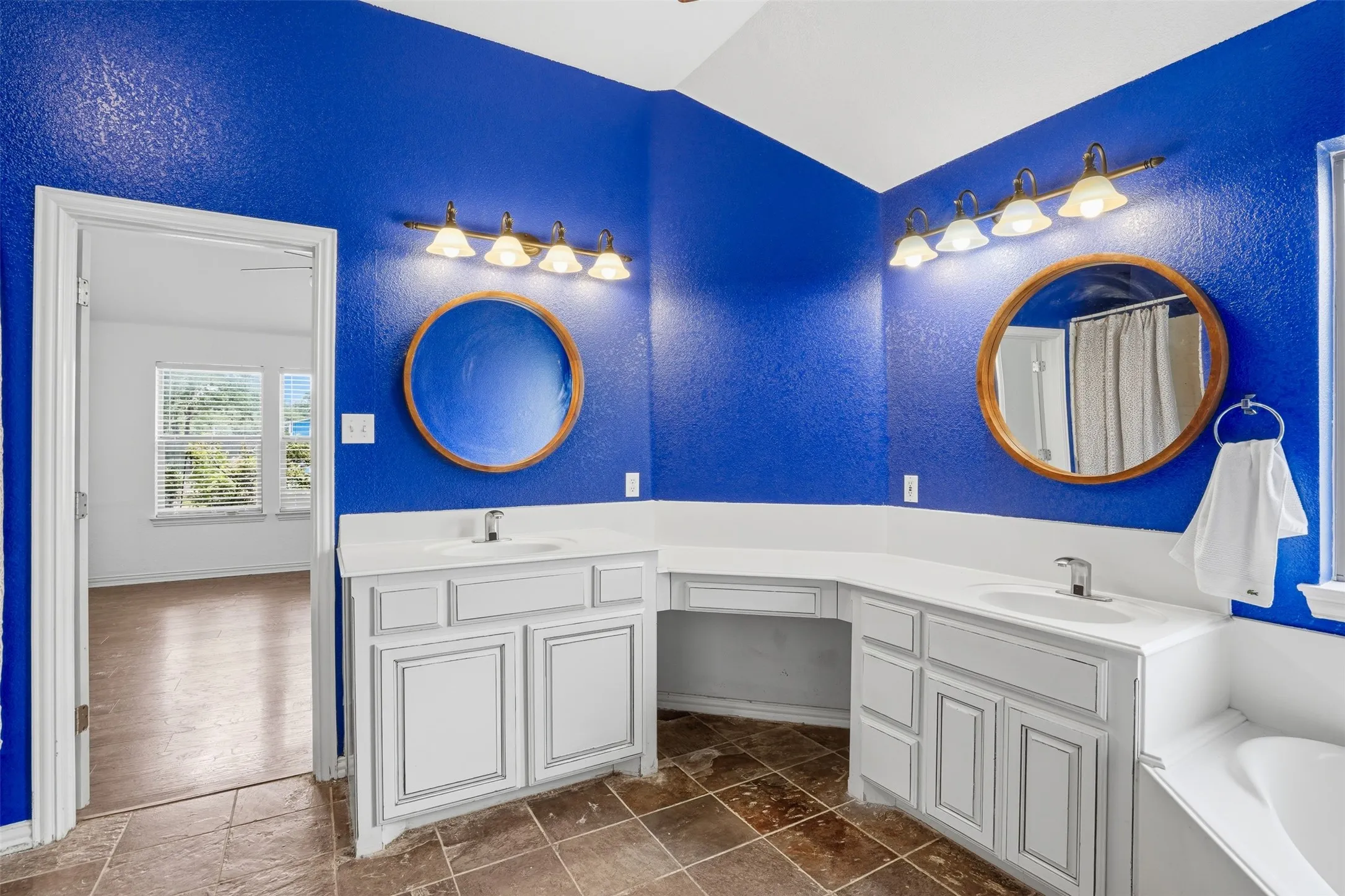 Dual vanity with white cabinetry, integrated sinks, white countertops, and circular mirrors