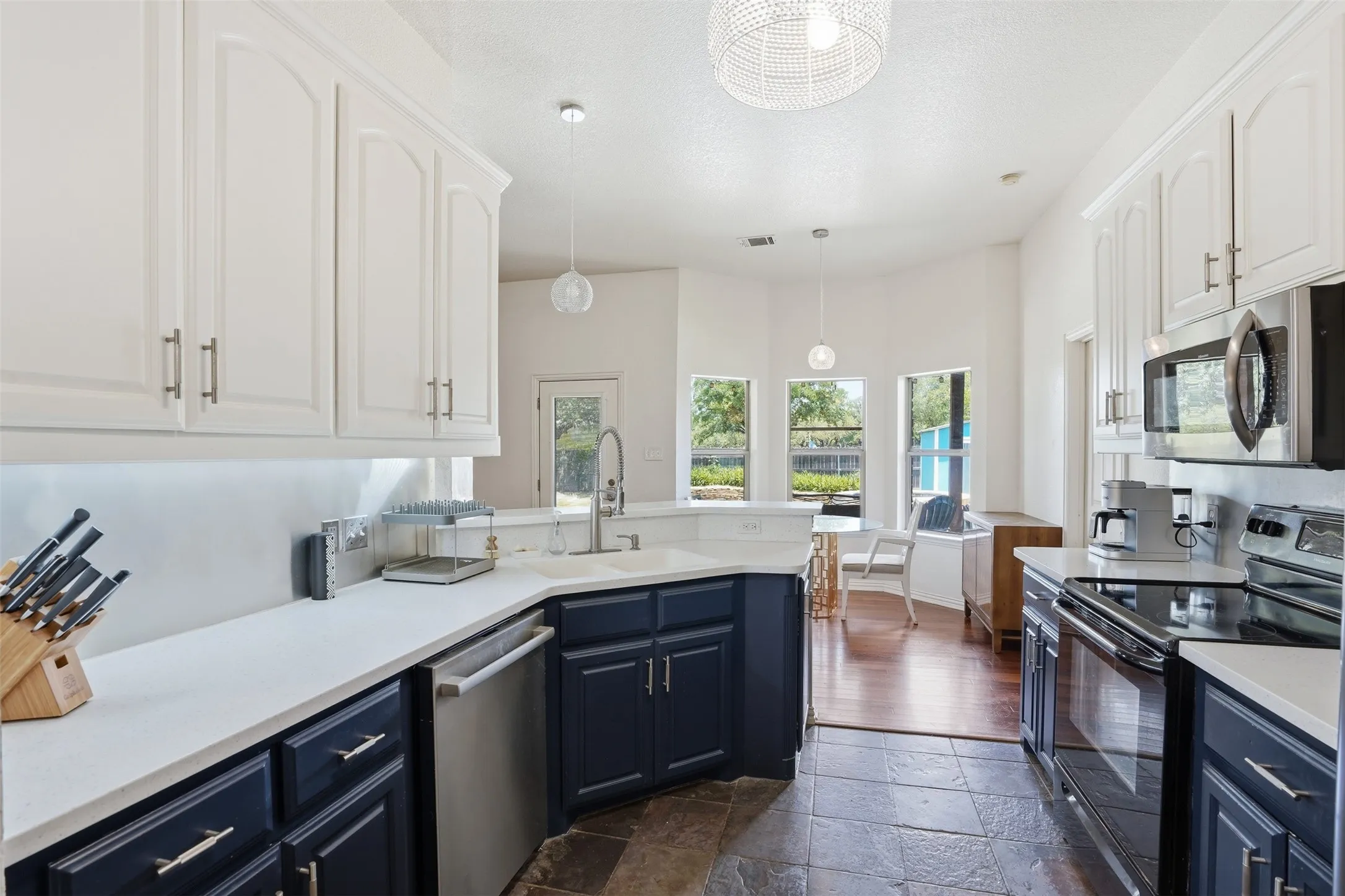 Kitchen featuring white upper cabinetry, navy blue lower cabinetry, white countertops, and stainless steel appliances