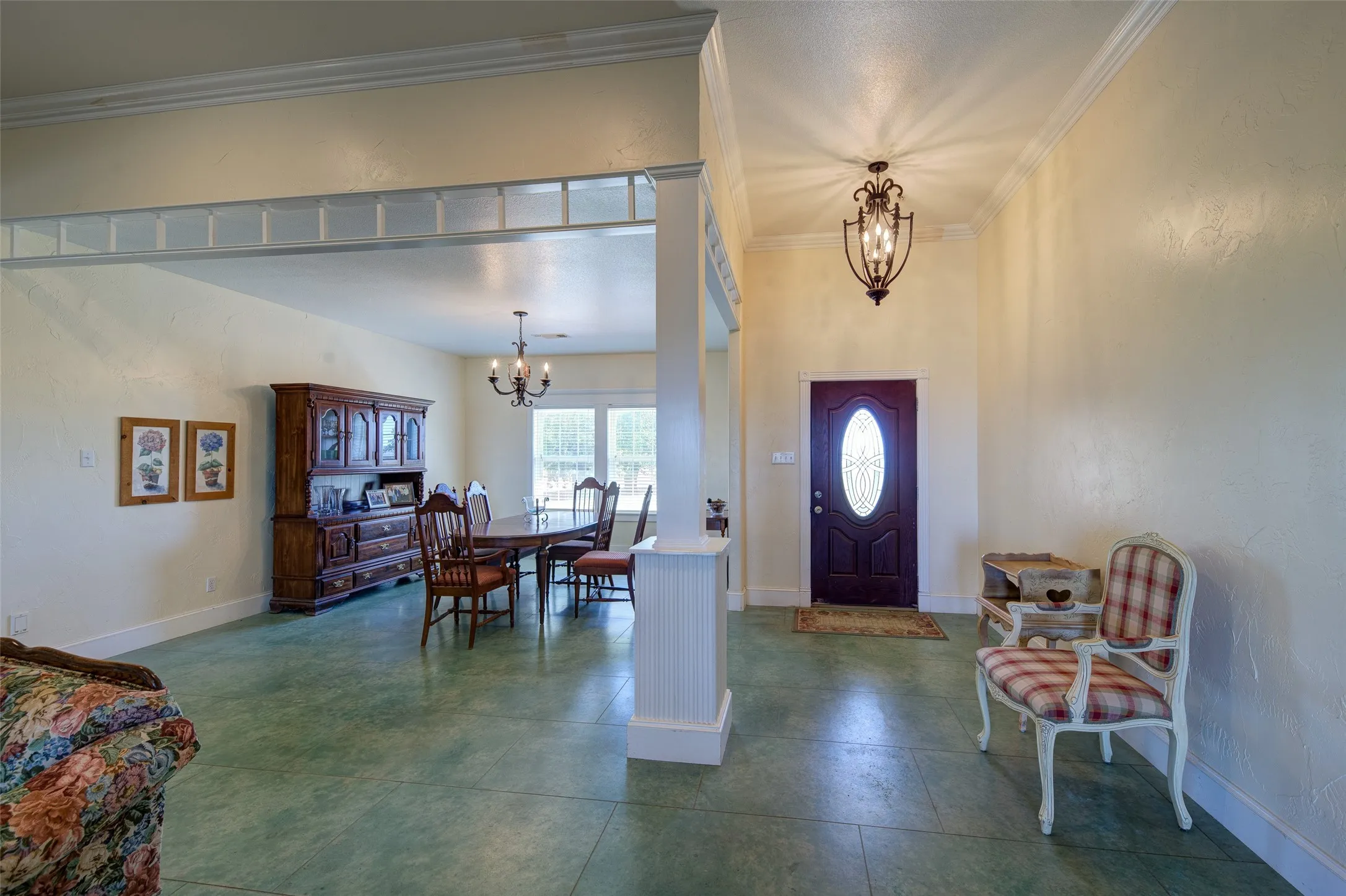 Spacious entry area with green-hued flooring, featuring a dark wood-finish door with an oval glass insert and a decorative overhead light fixture
