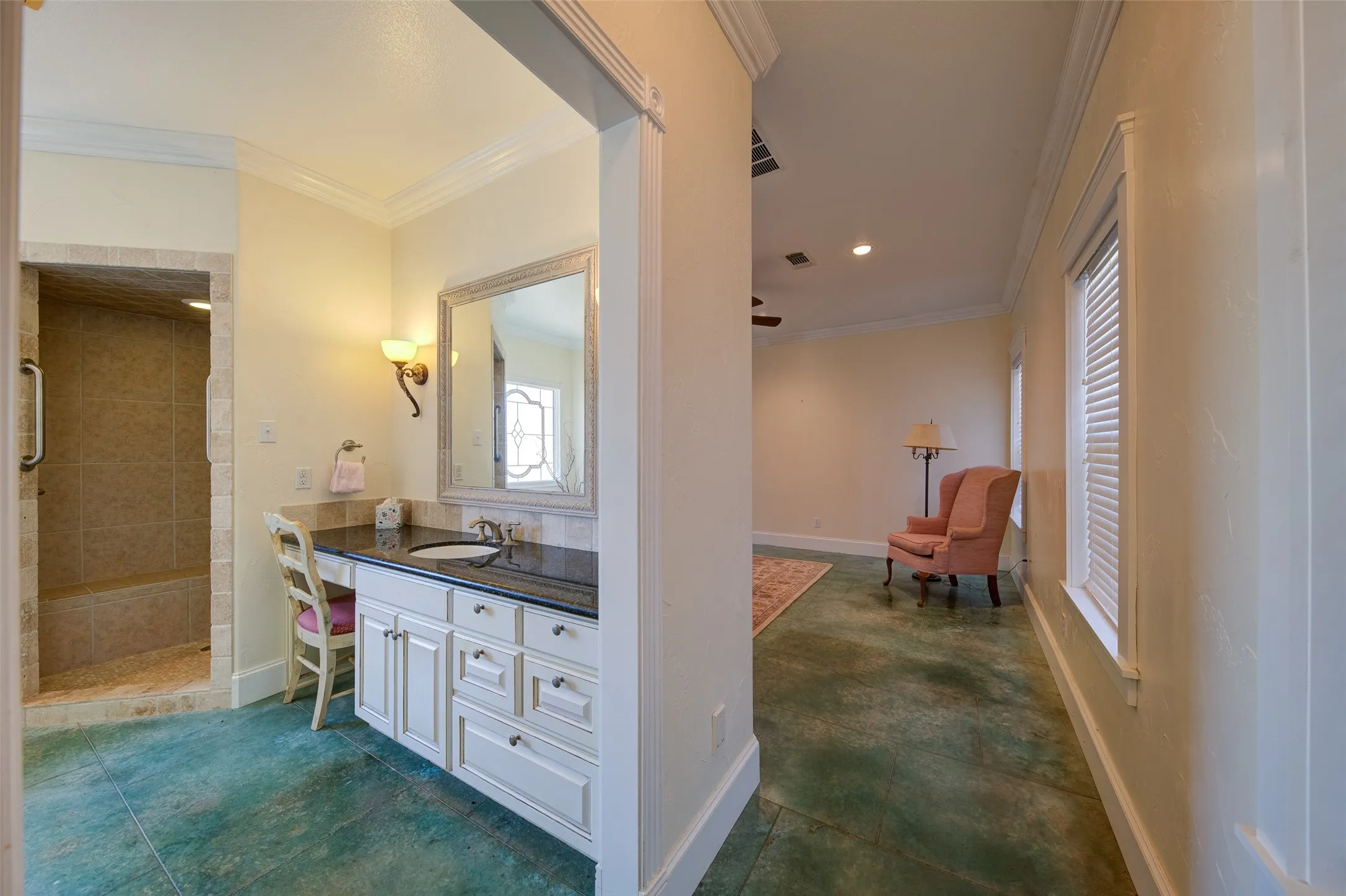 Bathroom vanity with a dark countertop and undermount sink, complemented by a large framed mirror and wall sconce lighting