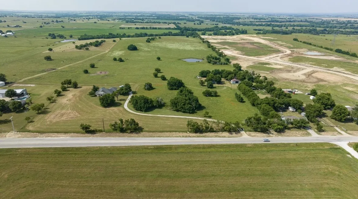 Expansive acreage featuring a single-story residence, a paved circular driveway, mature trees, and a pond