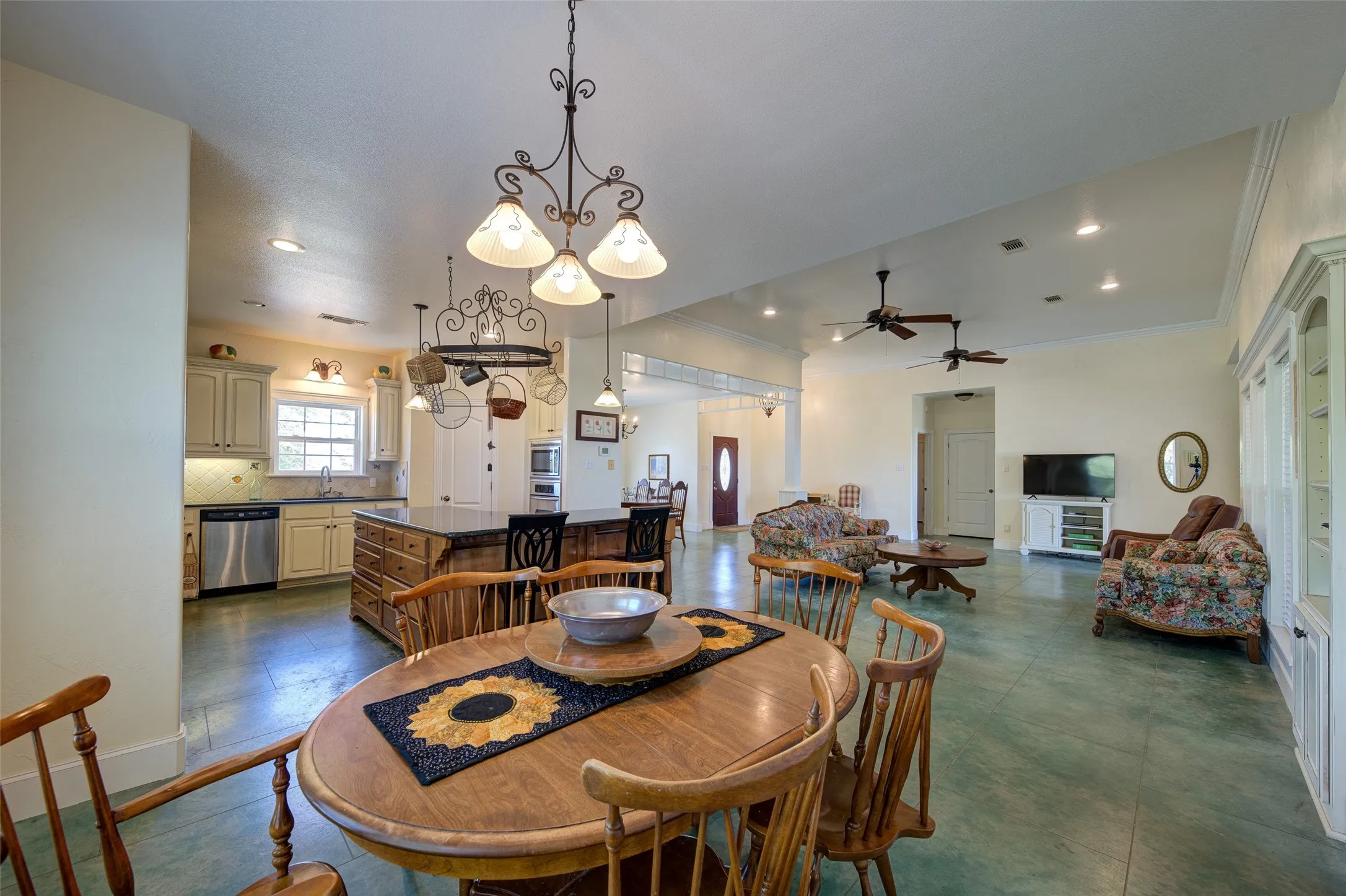 Open-concept interior featuring a kitchen with light-toned cabinetry, stainless steel appliances, and a central island with bar seating
