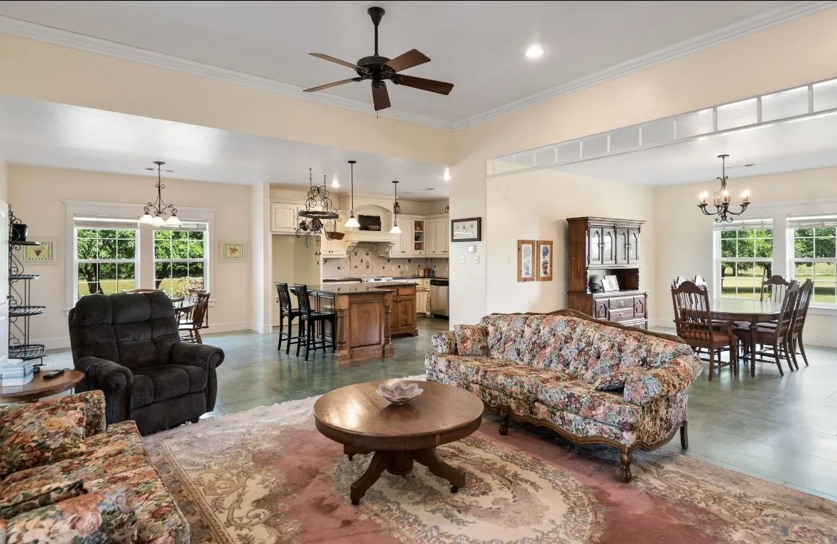 Spacious open-concept living area featuring multiple windows, a ceiling fan, crown molding, and recessed lighting
