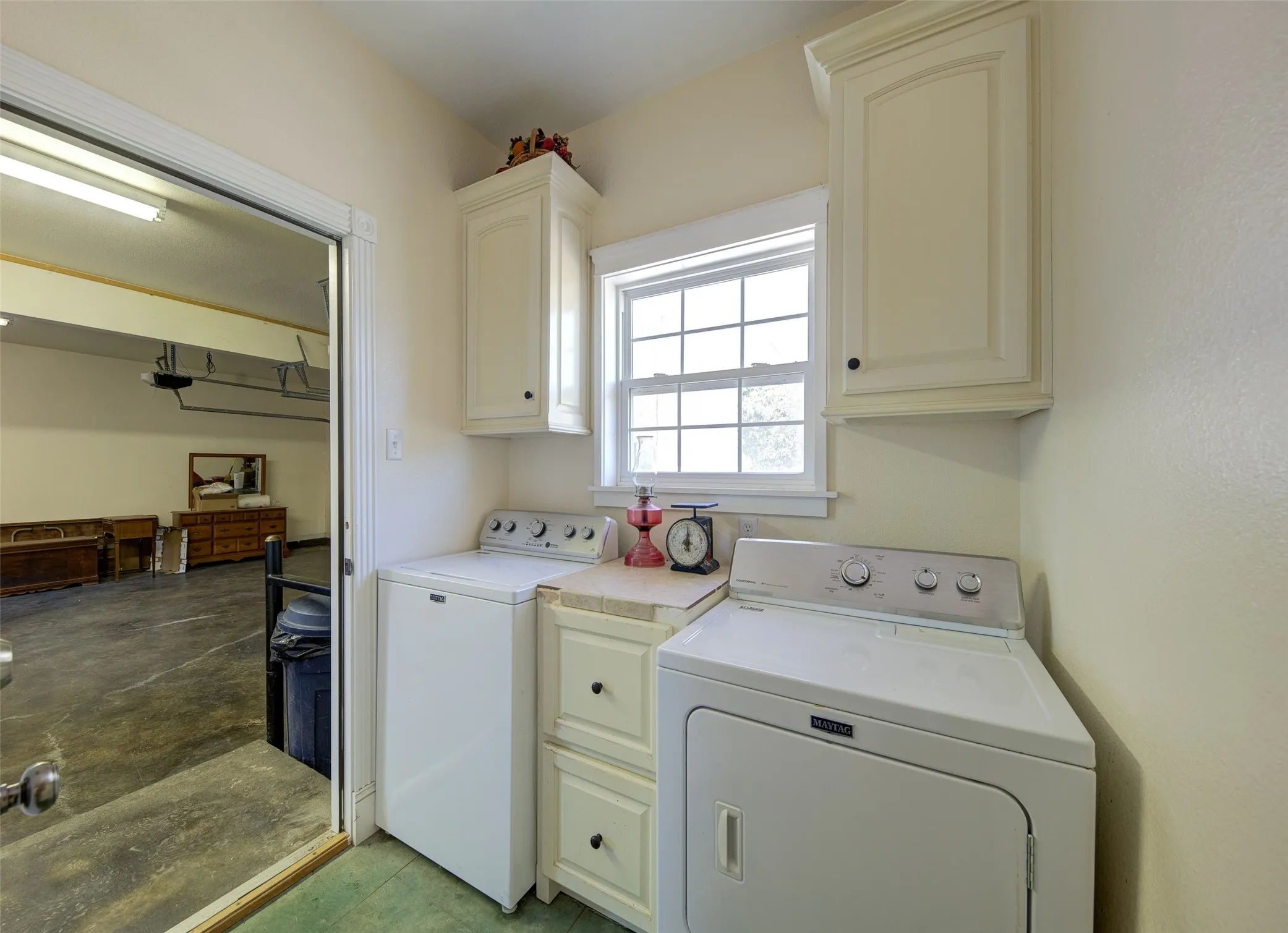 Laundry area featuring white cabinetry, a window with grid panes, and a countertop with built-in drawers