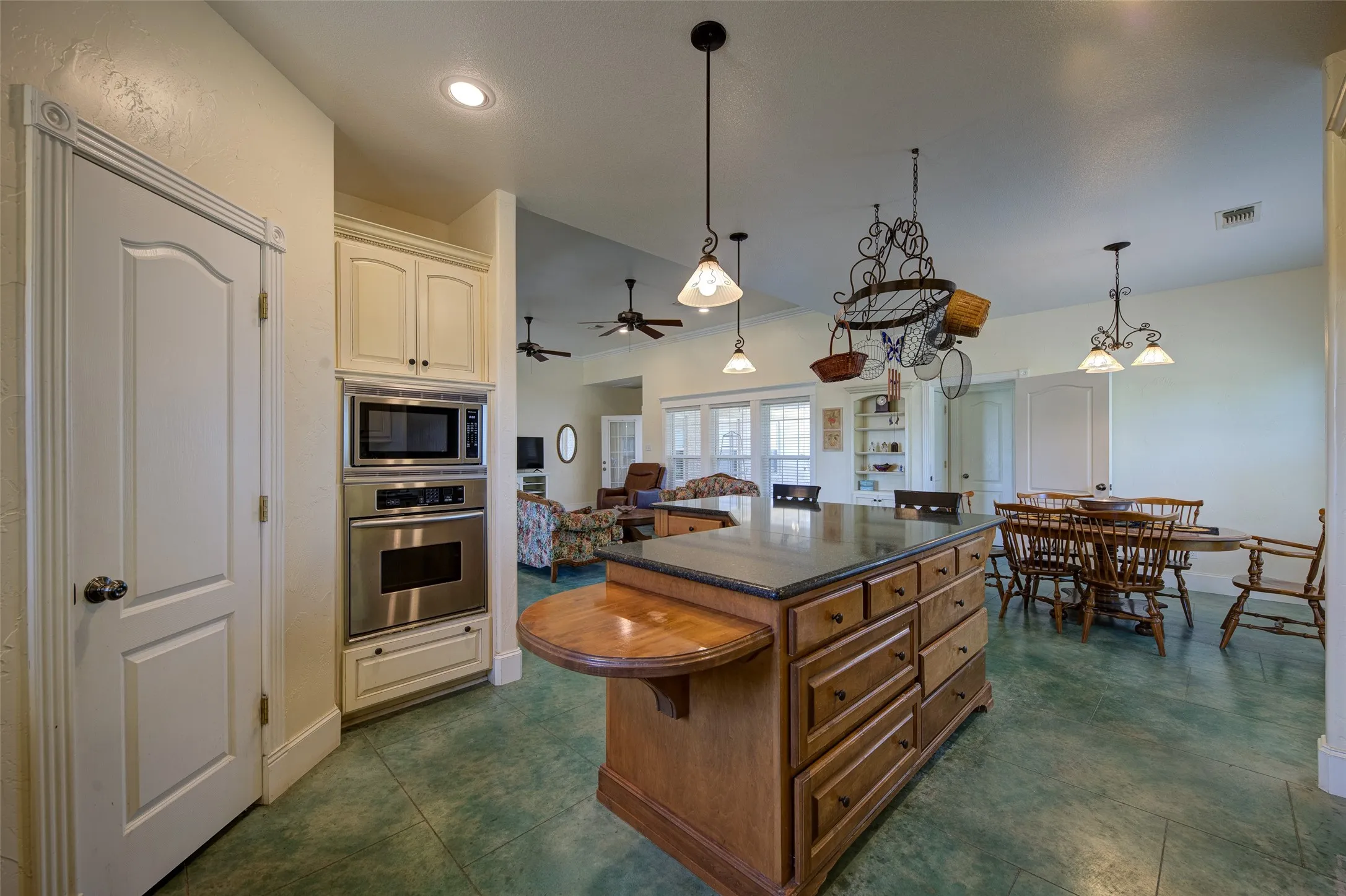 Open-concept kitchen featuring an expansive center island with a stone-finish countertop and warm wood cabinetry