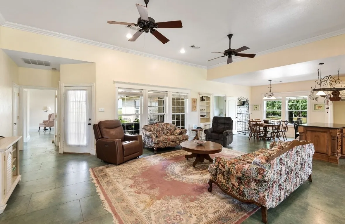 Spacious living area featuring high ceilings, ceiling fans, and multiple windows