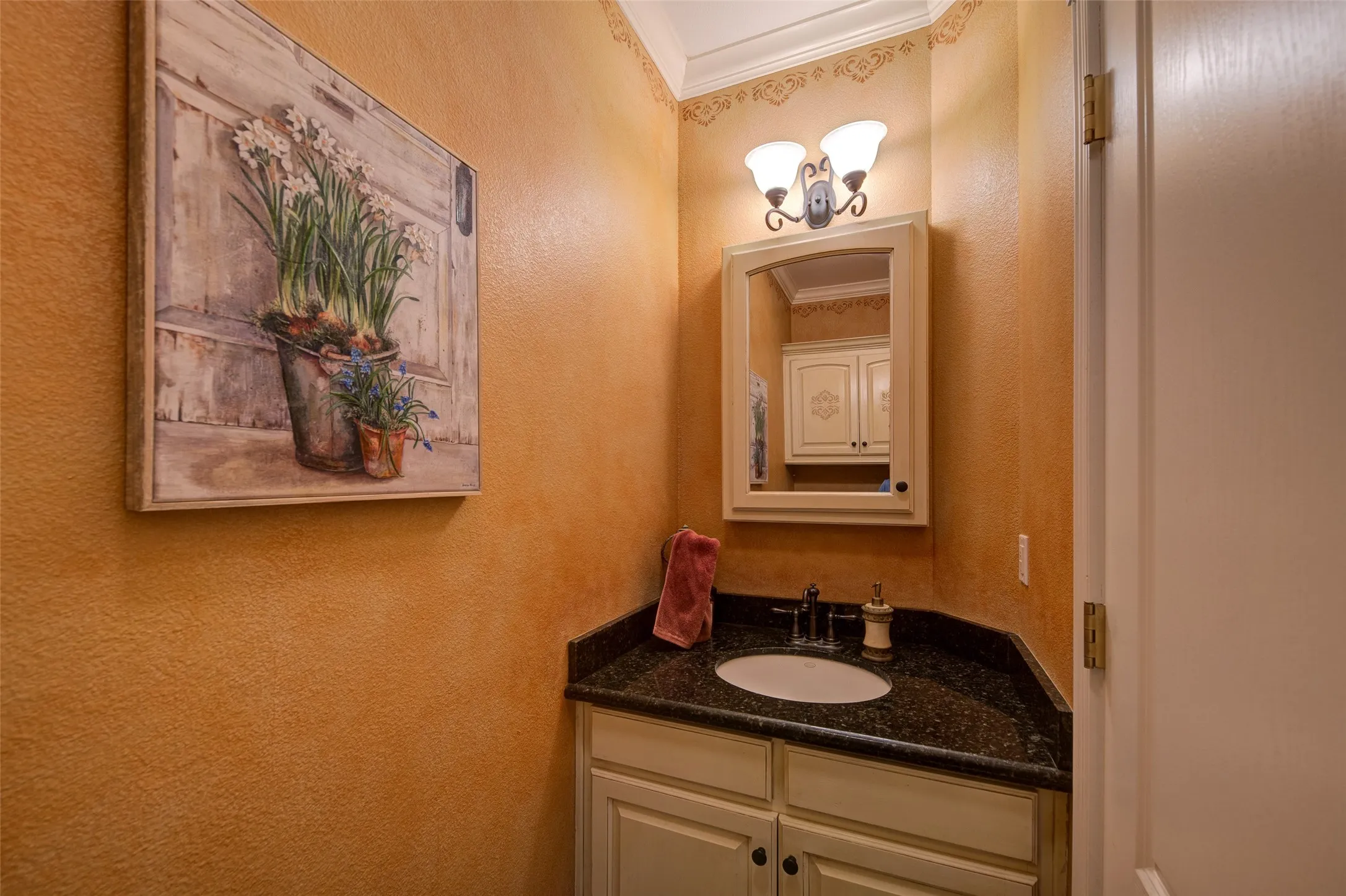 Vanity area featuring a built-in cabinet with recessed panel doors, a dark speckled countertop, and an undermount sink with a dark-finish faucet