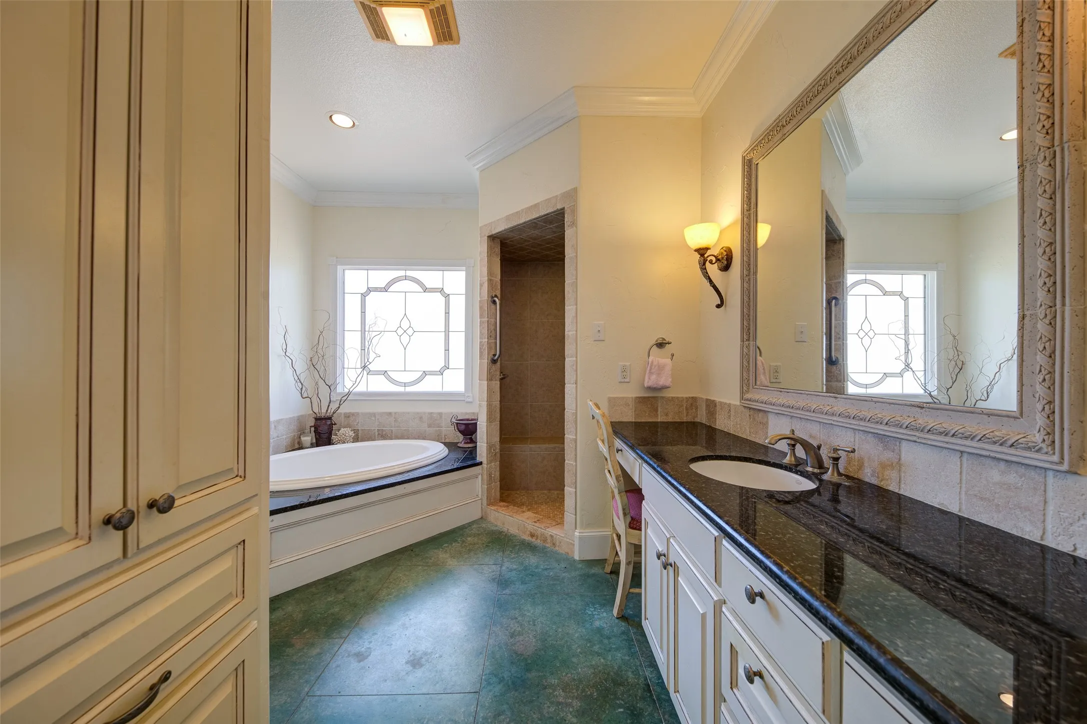 Dual vanity with black countertop and undermount sink, framed mirror, and decorative wall sconces