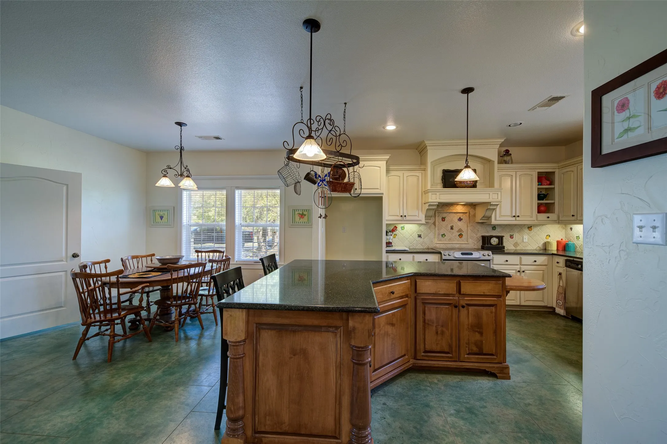 Open-concept kitchen and dining area featuring a central island with a dark countertop and wood cabinetry