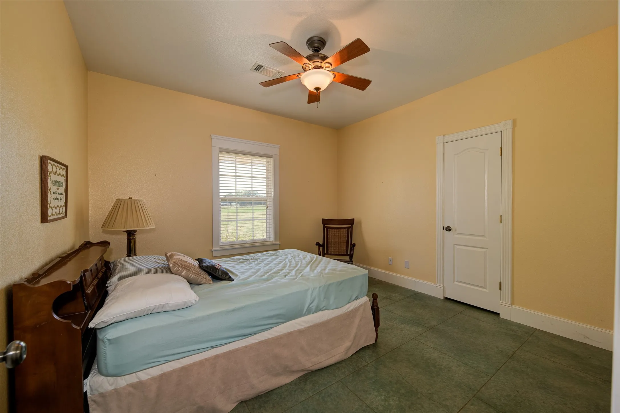 Bedroom featuring a ceiling fan with integrated lighting, a window with blinds, a paneled door, and green tile flooring