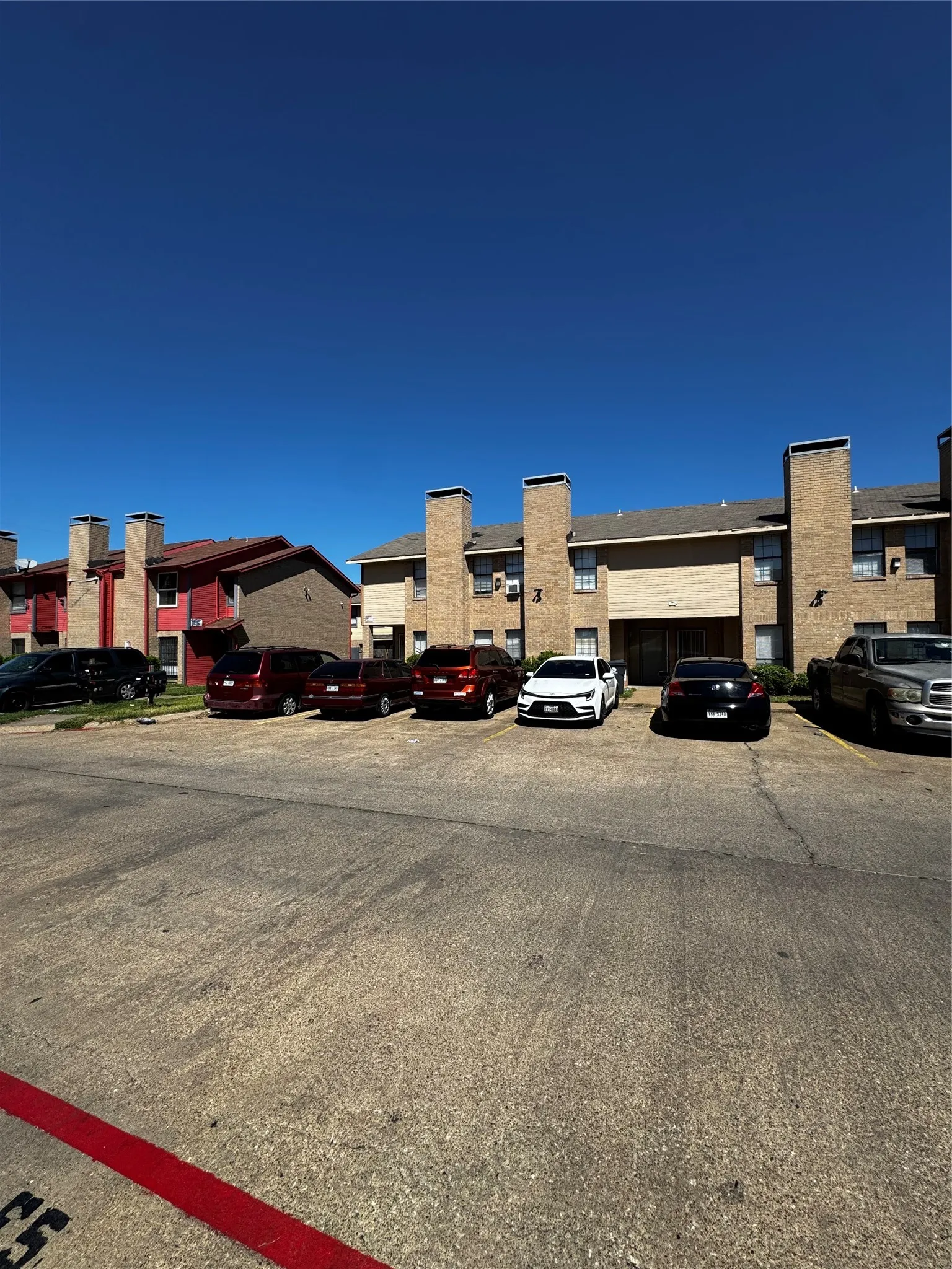 Multi-story property featuring brick facades and multiple chimneys, with a paved parking area