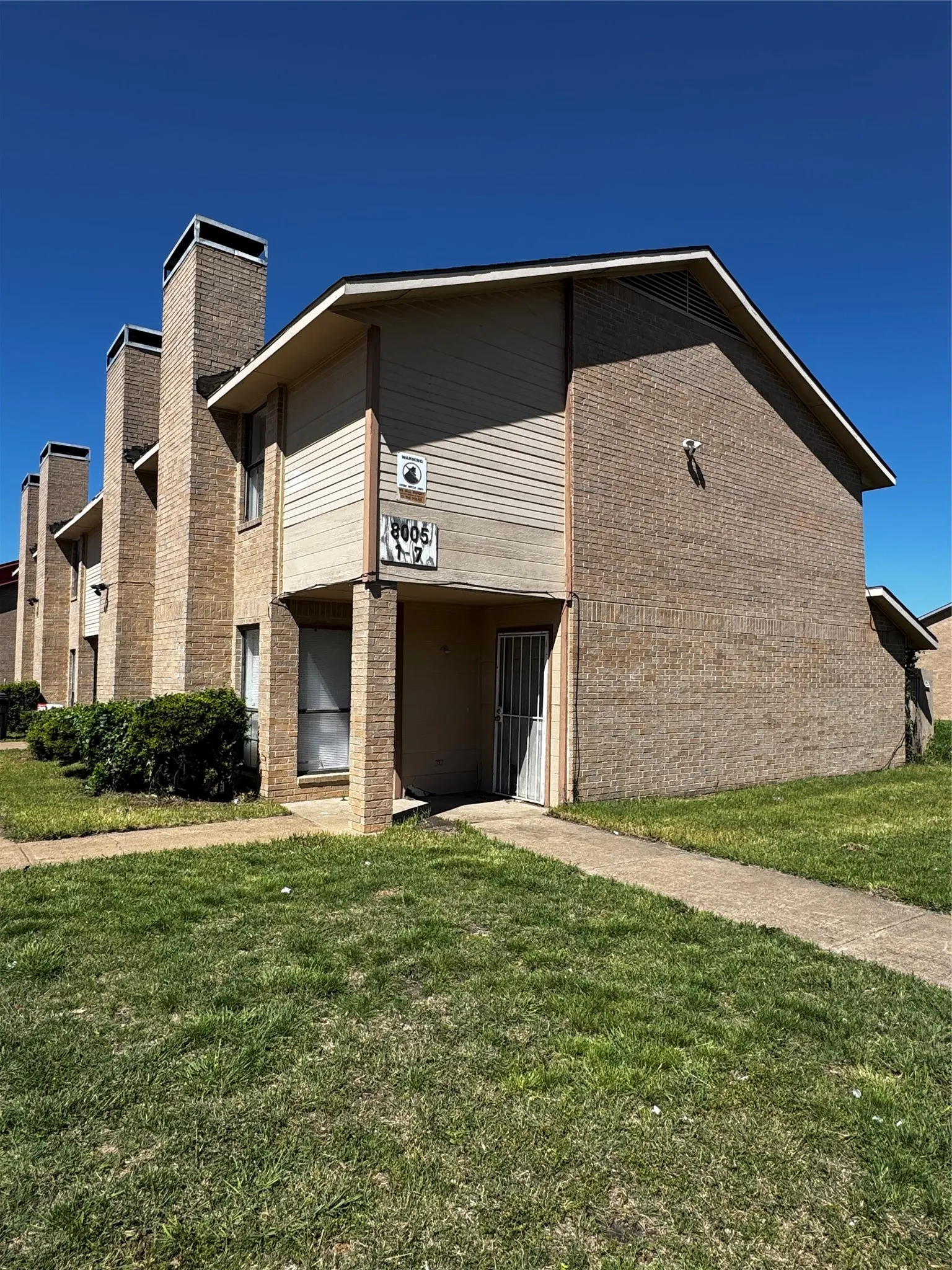 Two-story brick and siding structure featuring multiple chimney stacks, a sloped roofline, and an integrated entrance alcove