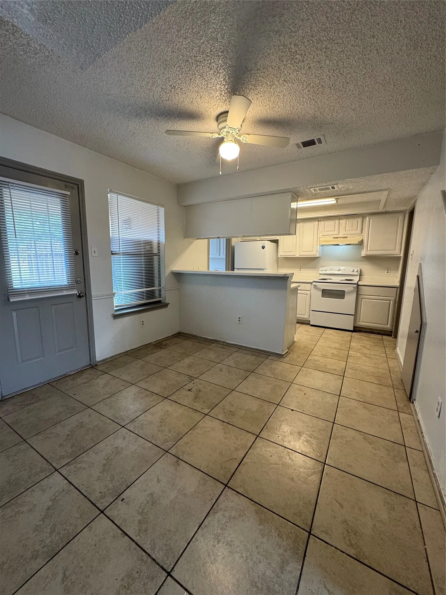 Kitchen and dining area featuring tile flooring, white cabinetry, a white electric range, and a ceiling fan with integrated lighting
