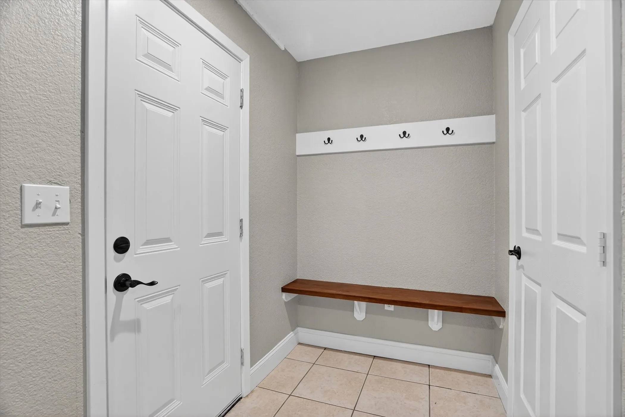 Entryway featuring a built-in wood-finish bench, coat rack with black hooks, and neutral-toned wall paint