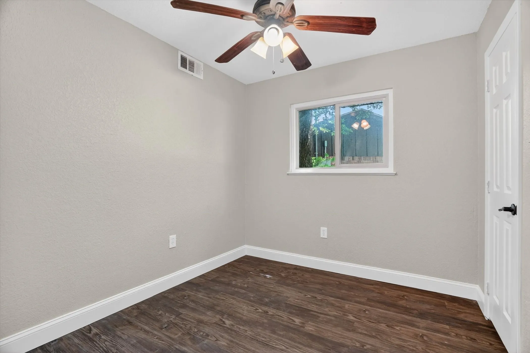 Wood-finish flooring with white baseboards, light neutral wall paint, and a ceiling fan with integrated lighting