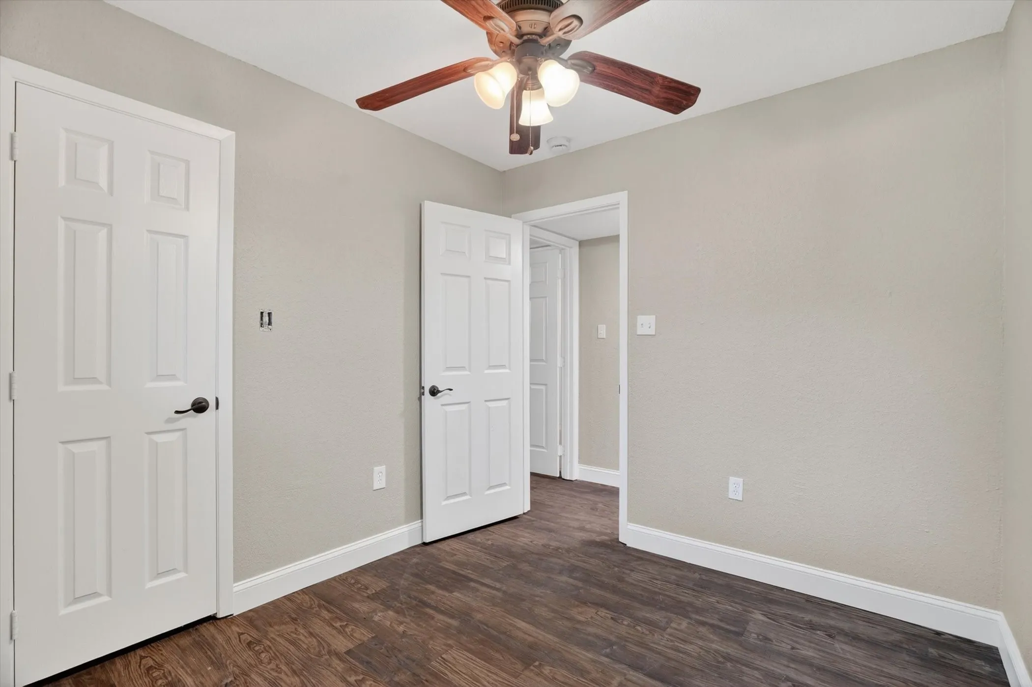 Room featuring wood-finish flooring, light neutral wall paint, and white trim