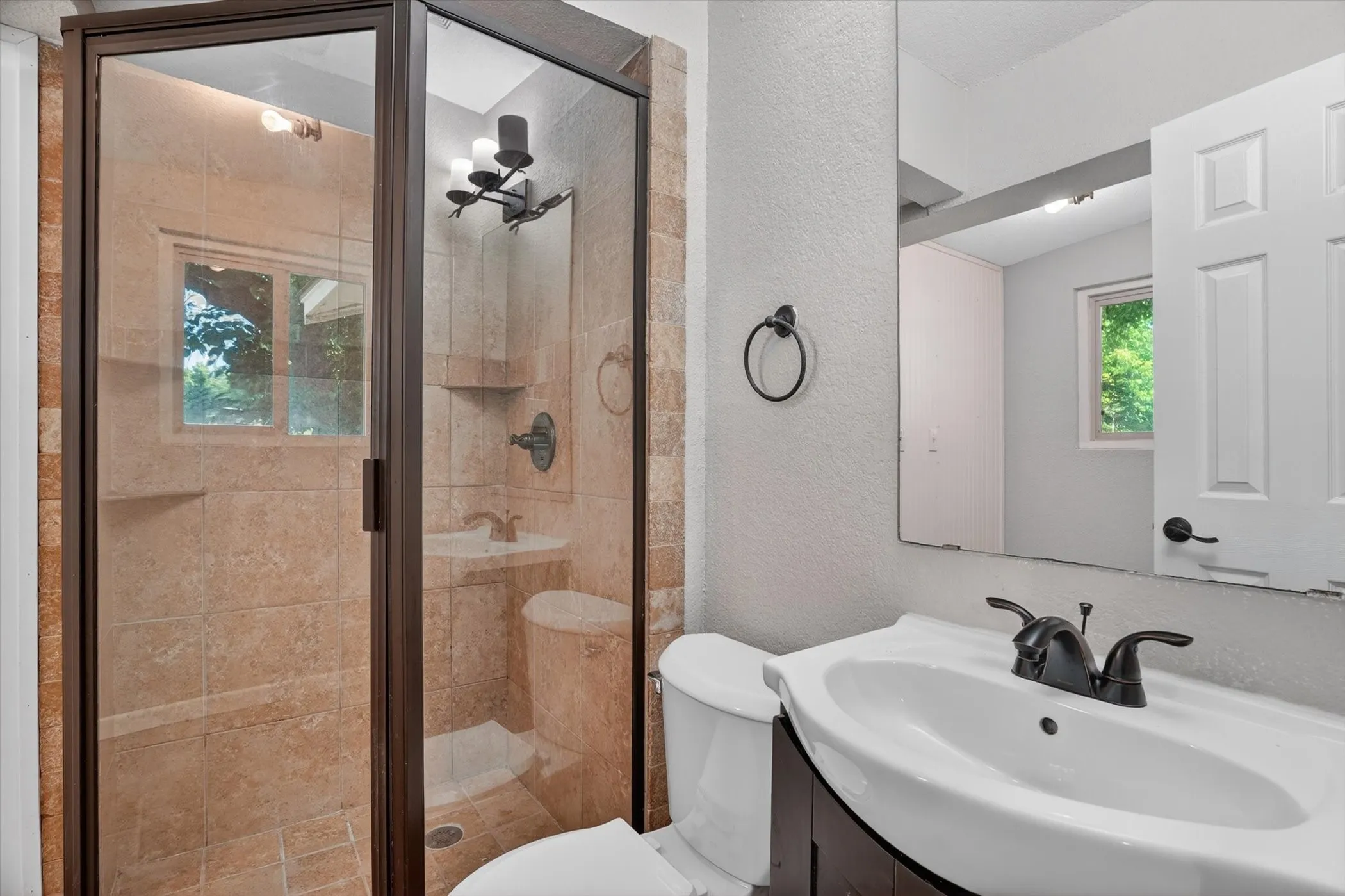 Framed glass shower enclosure featuring full-height tile surround, built-in shelving, and a window