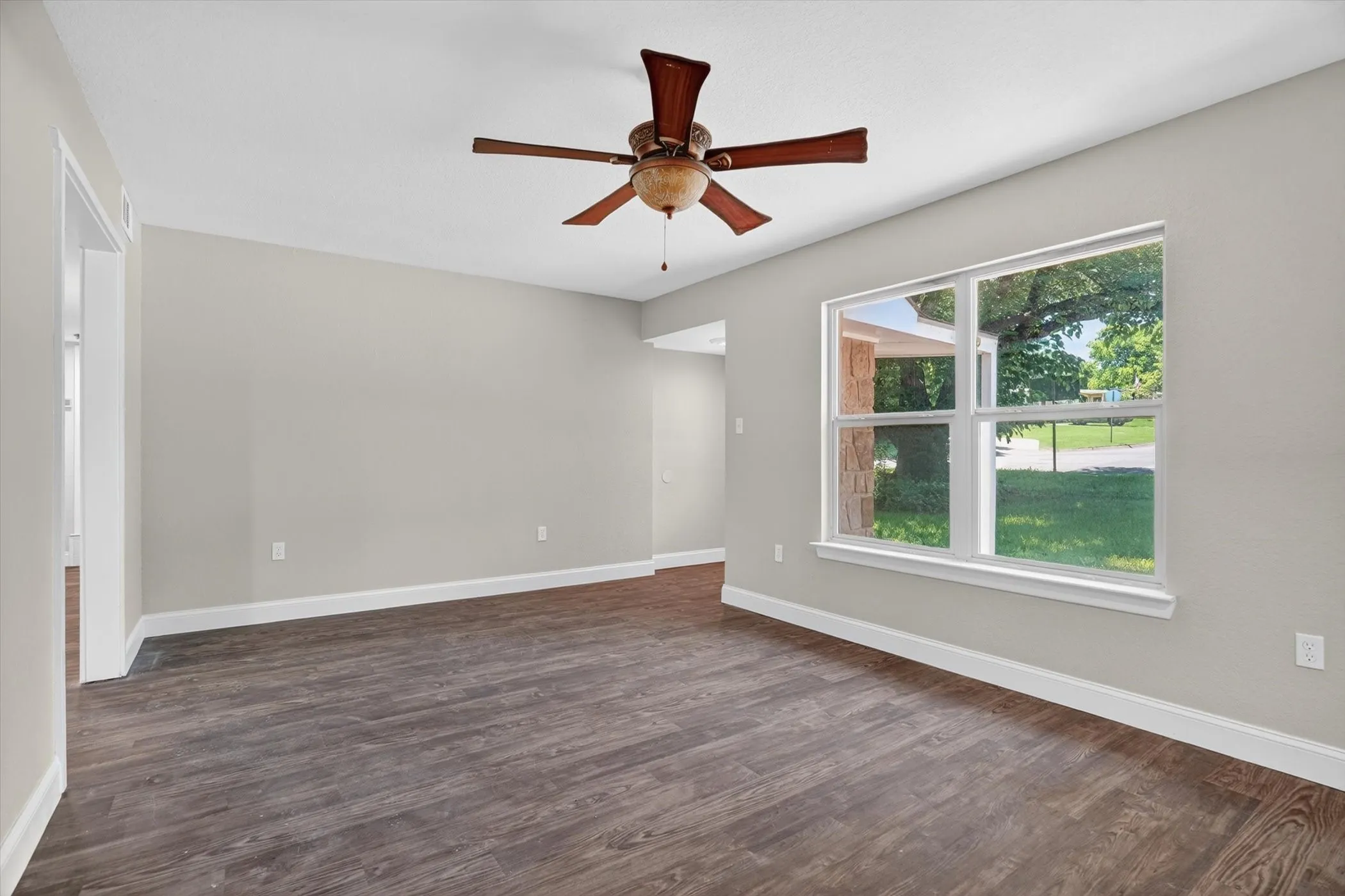 Spacious room featuring wood-finish flooring, light gray walls, and white trim