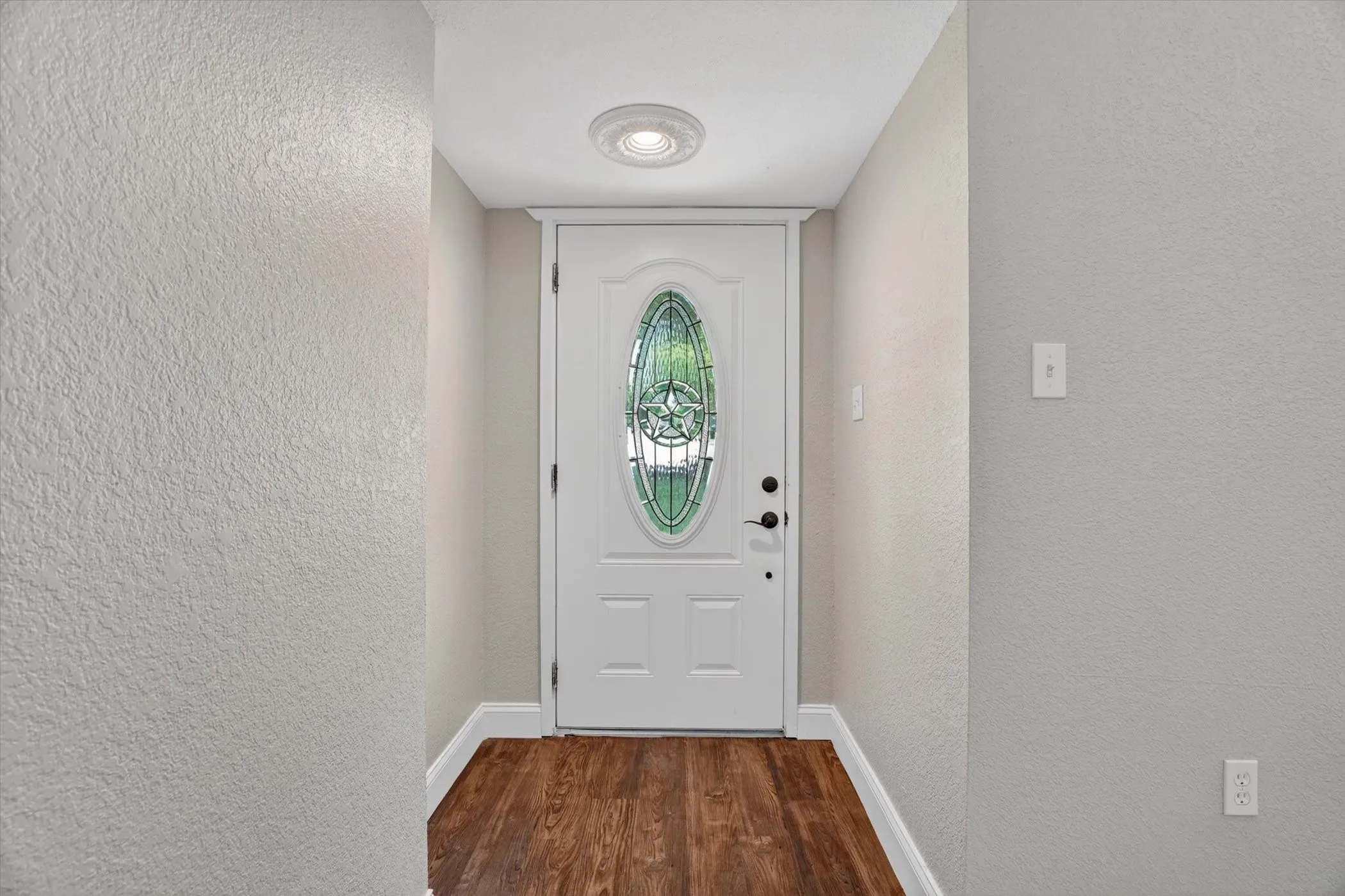 Entryway featuring a white paneled door with an oval stained-glass insert
