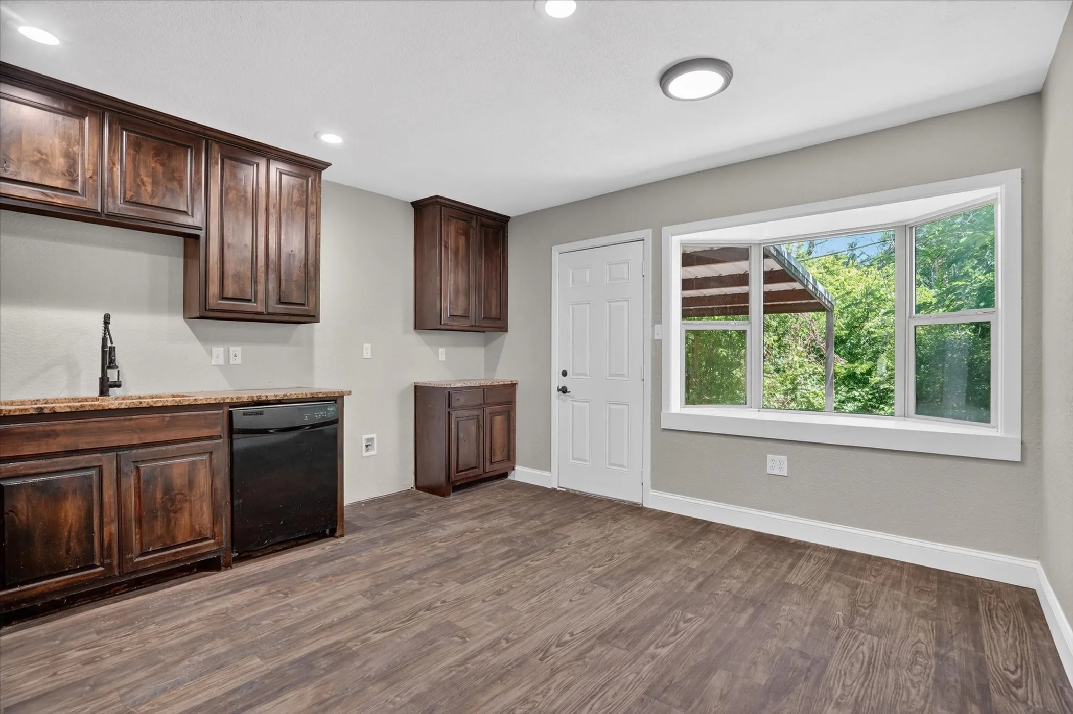 Kitchen area featuring rich wood cabinetry, stone-finish countertops, and wood-finish flooring