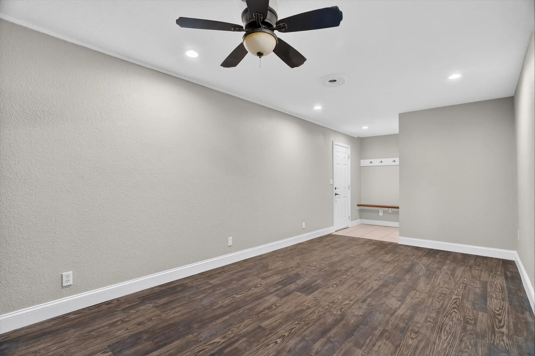 Spacious room featuring wood-finish flooring, recessed lighting, and a ceiling fan