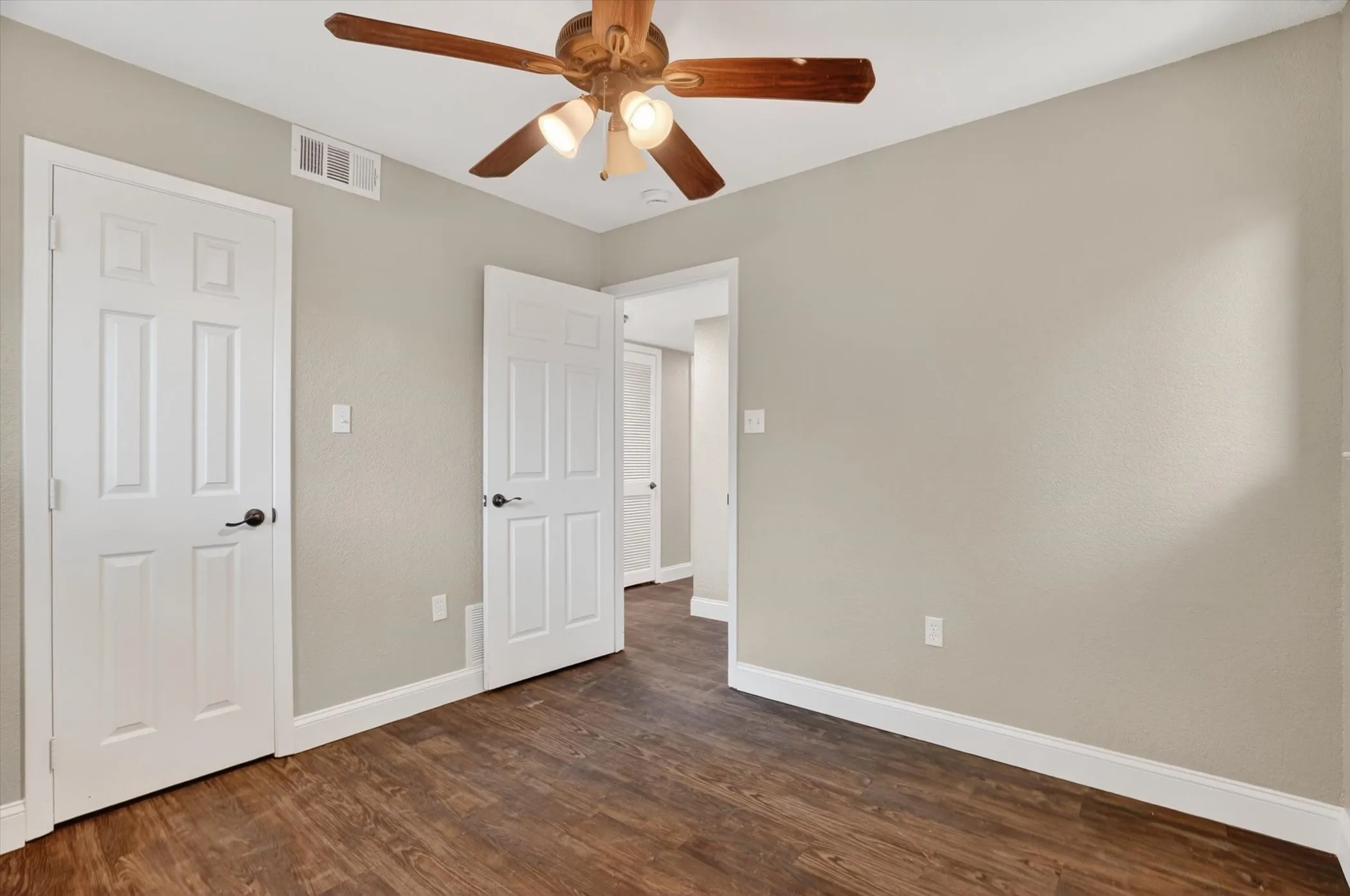 Room featuring wood-finish flooring, light neutral wall paint, and white trim