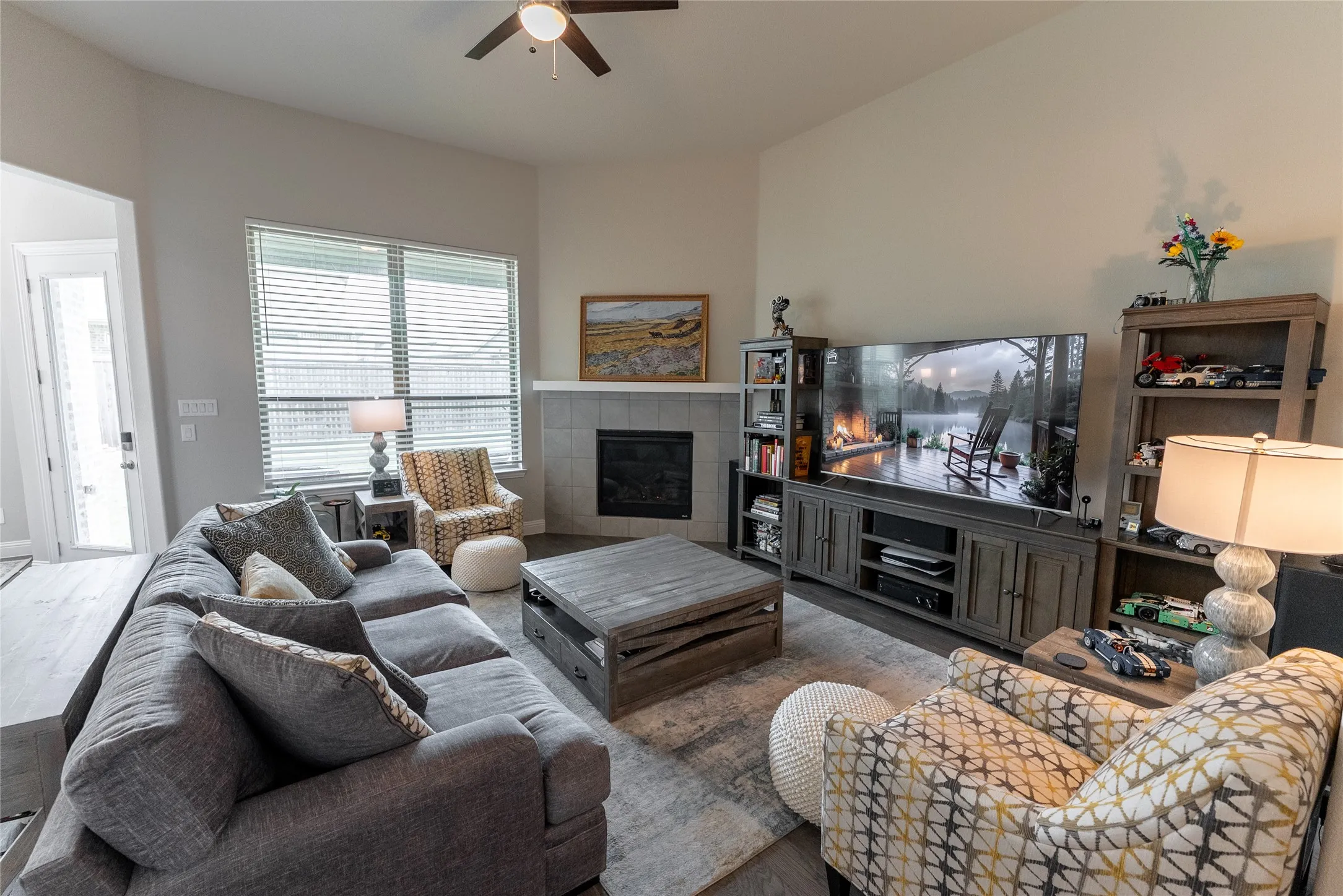 Living room with ceiling fan, LVP flooring and fireplace.