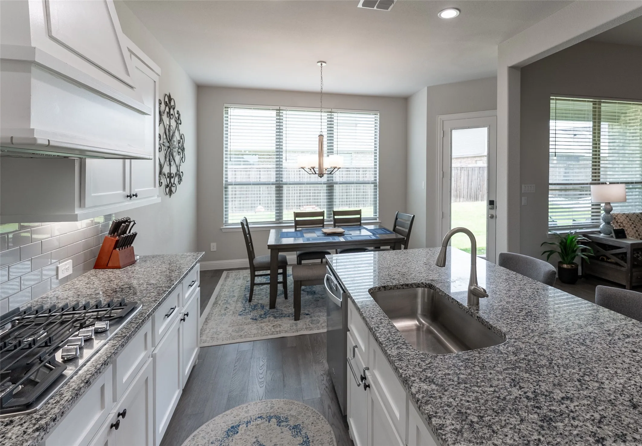 Kitchen with LVP flooring, granite countertops, gas stove, hood, and built-in microwave and oven.