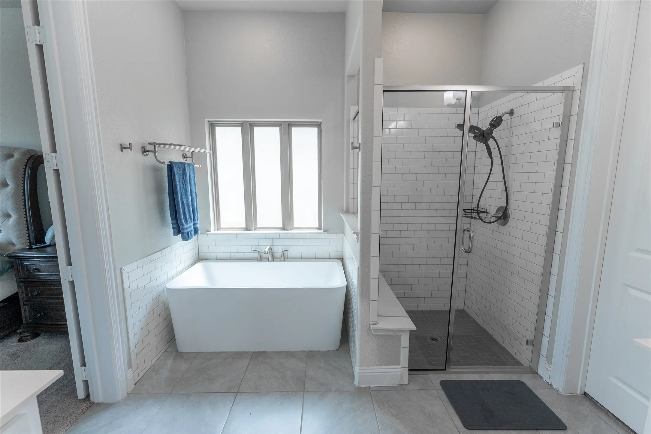 Primary bathroom featuring a free standing tub, separate shower, separate vanities, walk in closet and tile floors.