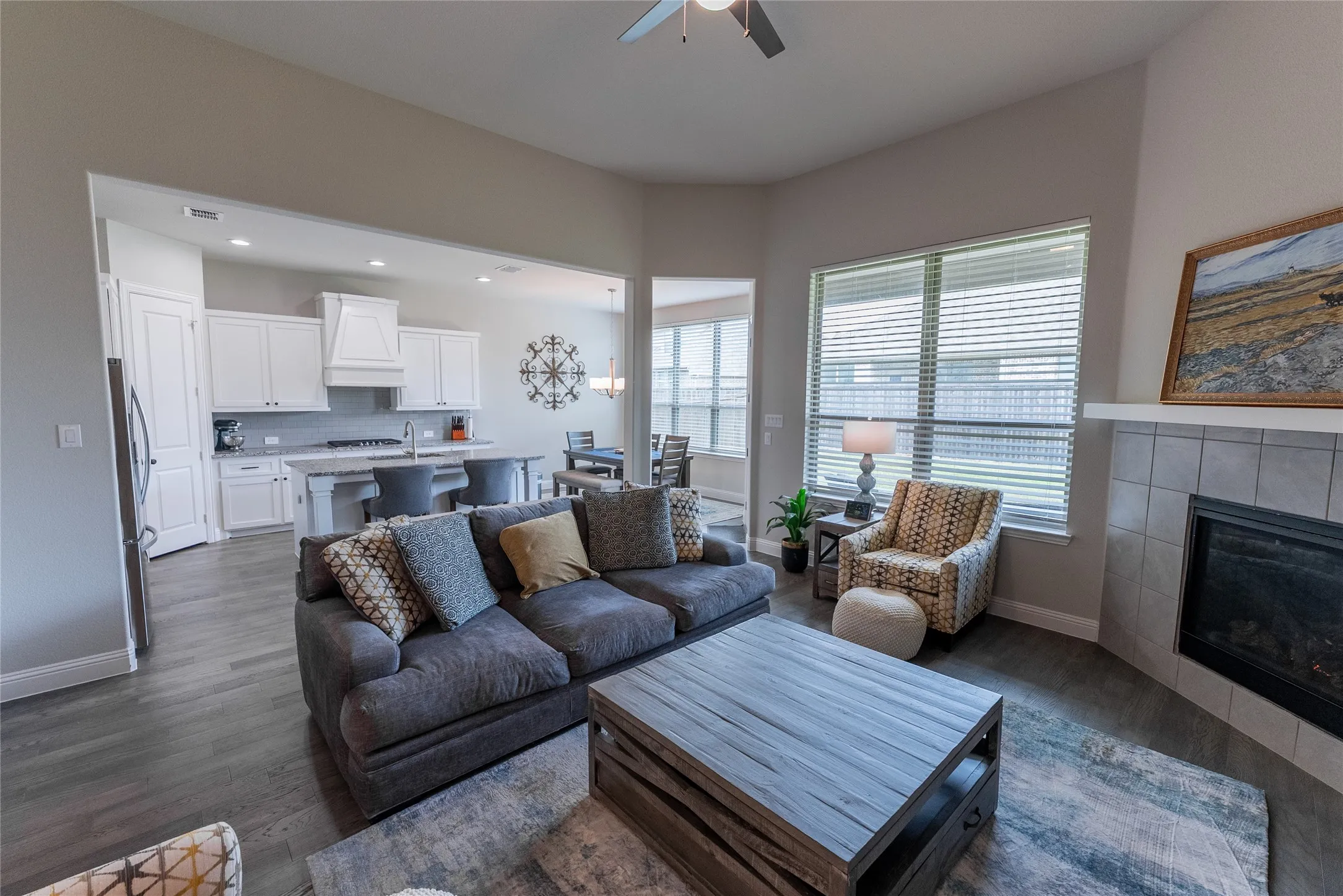 Living room with ceiling fan, LVP flooring and fireplace.