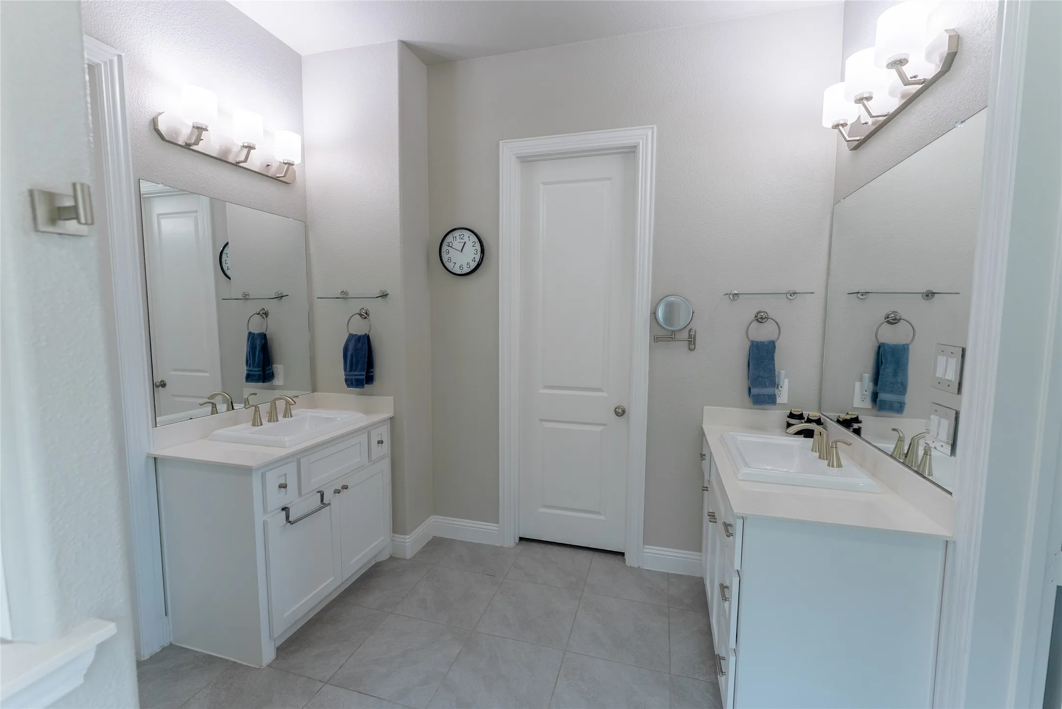 Primary bathroom featuring a free standing tub, separate shower, separate vanities, walk in closet and tile floors.