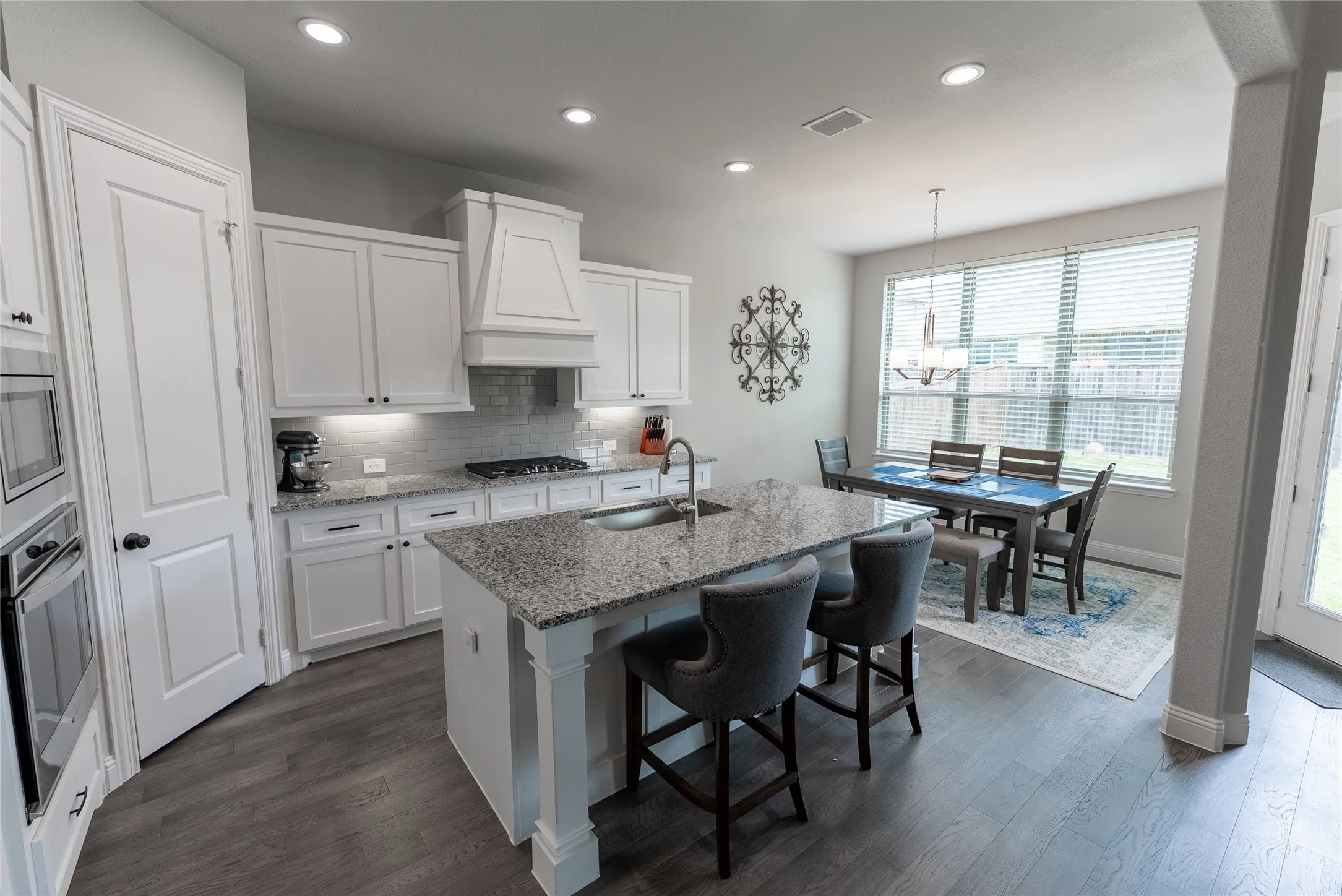Kitchen with LVP flooring, granite countertops, gas stove, hood, and built-in microwave and oven.