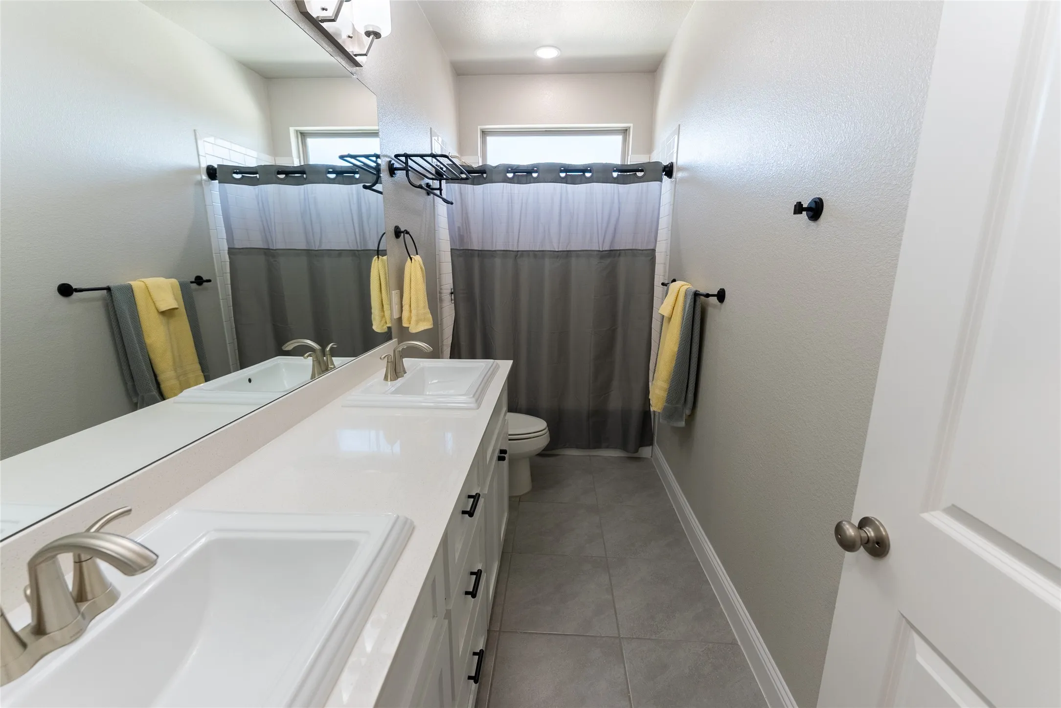 Upstairs bathroom featuring tile flooring and double vanities.