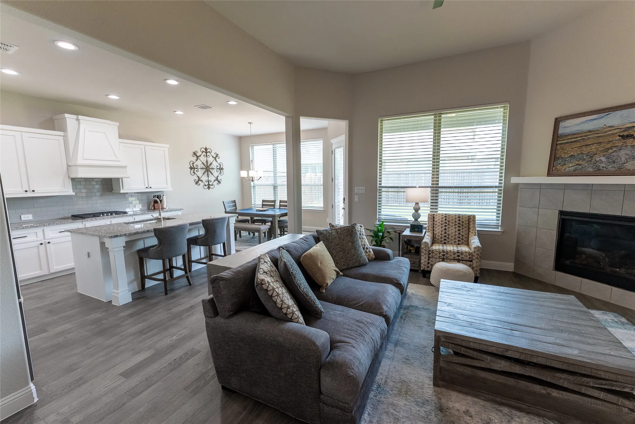 Living room with ceiling fan, LVP flooring and fireplace.
