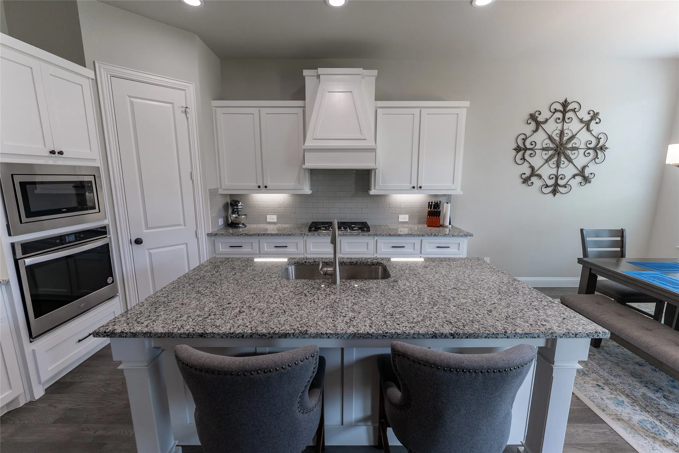 Kitchen with LVP flooring, granite countertops, gas stove, hood, and built-in microwave and oven.