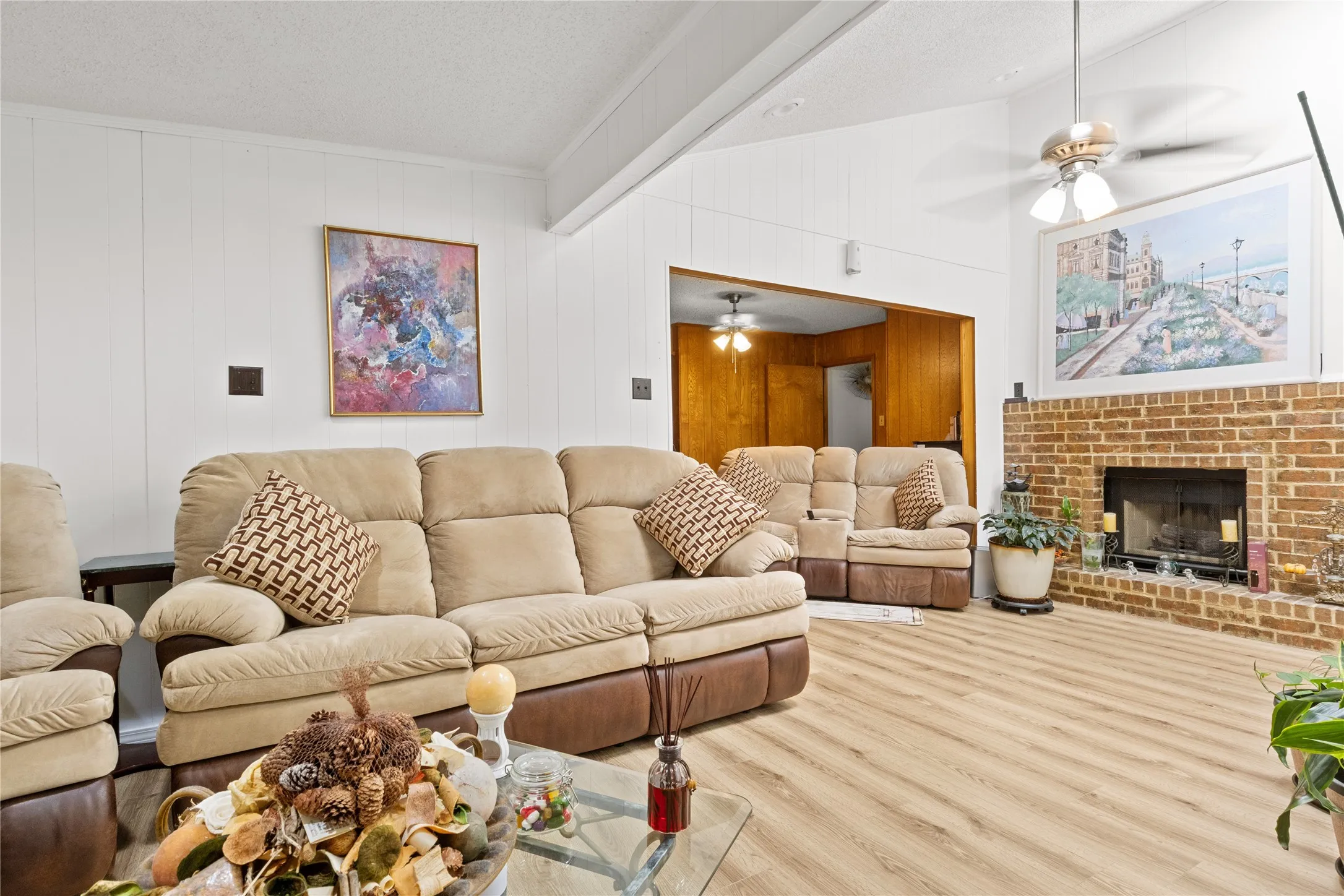 Vaulted ceiling den (Empty)  featuring wood-finish flooring, a brick fireplace, and white paneling