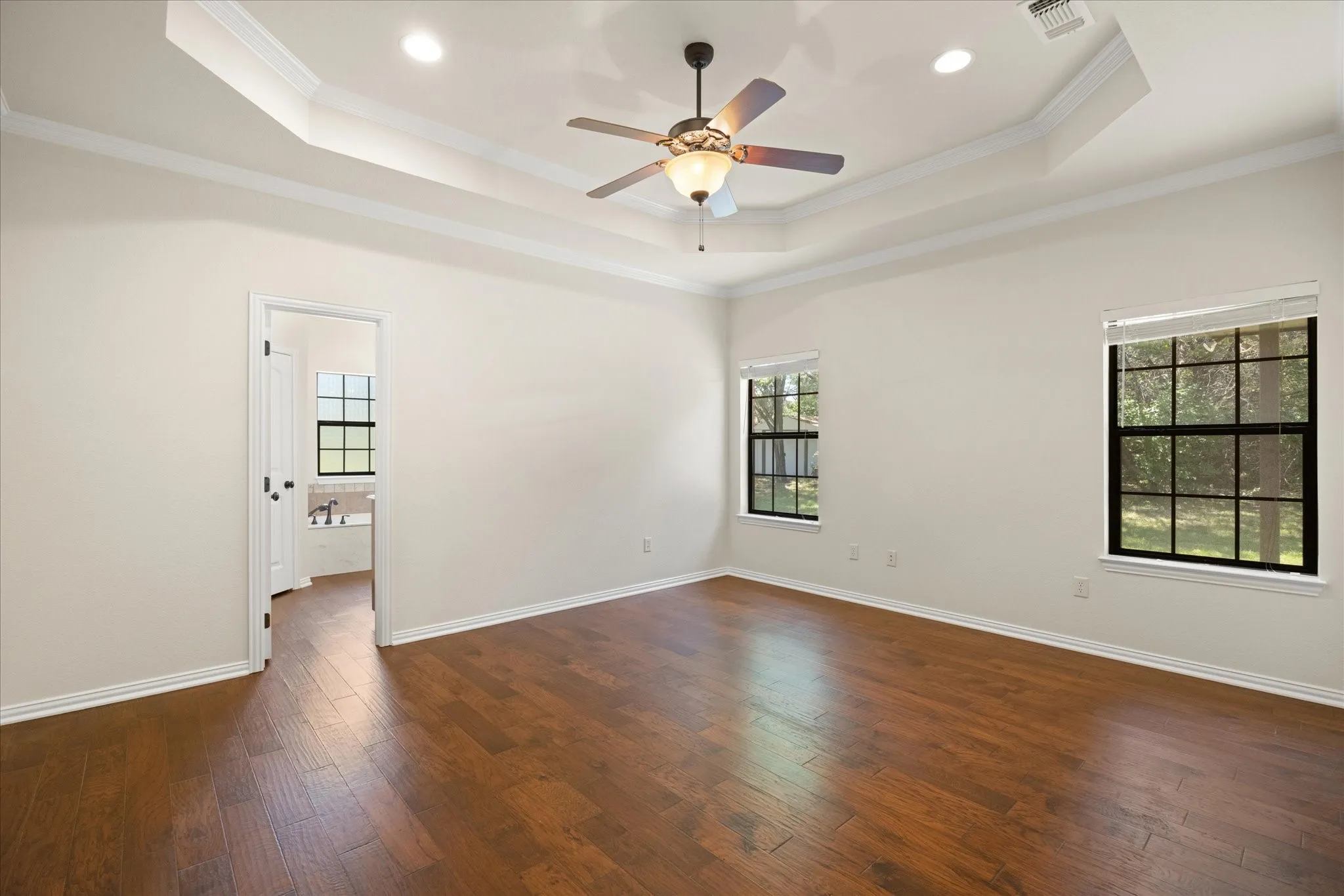 Primary bedroom with engineered hardwood floors and natural lighting