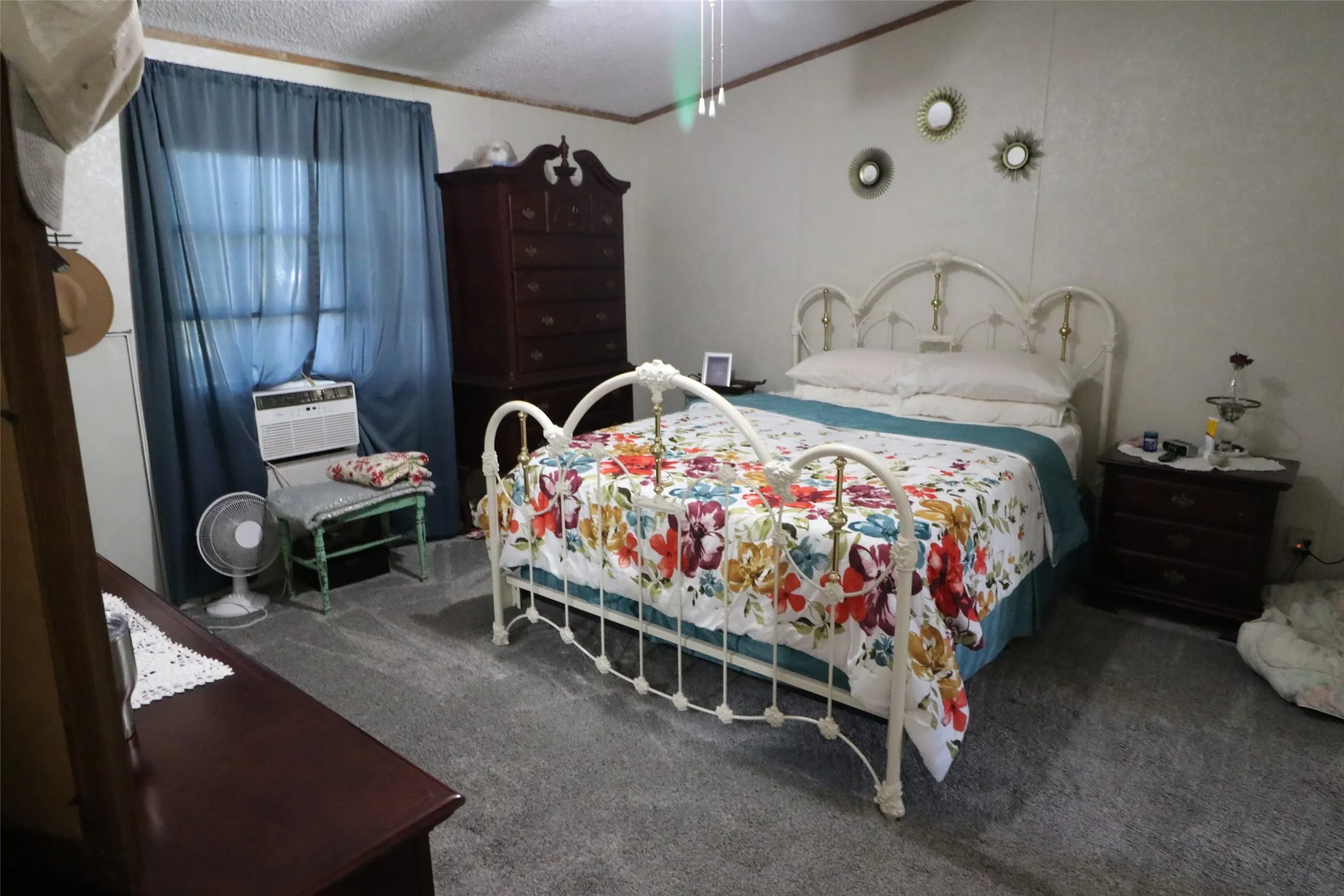 Carpeted room with a ceiling fan, a window with blue curtains, and light-toned walls