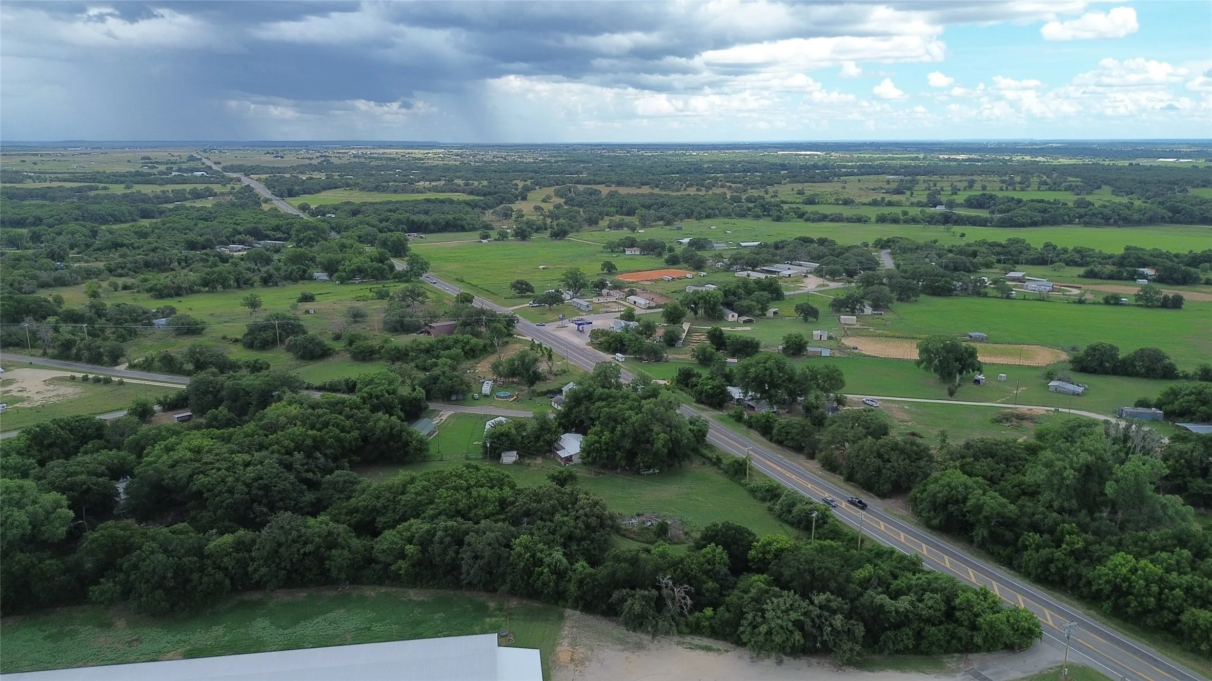 Expansive aerial perspective showcasing a rural landscape with abundant mature trees and verdant fields
