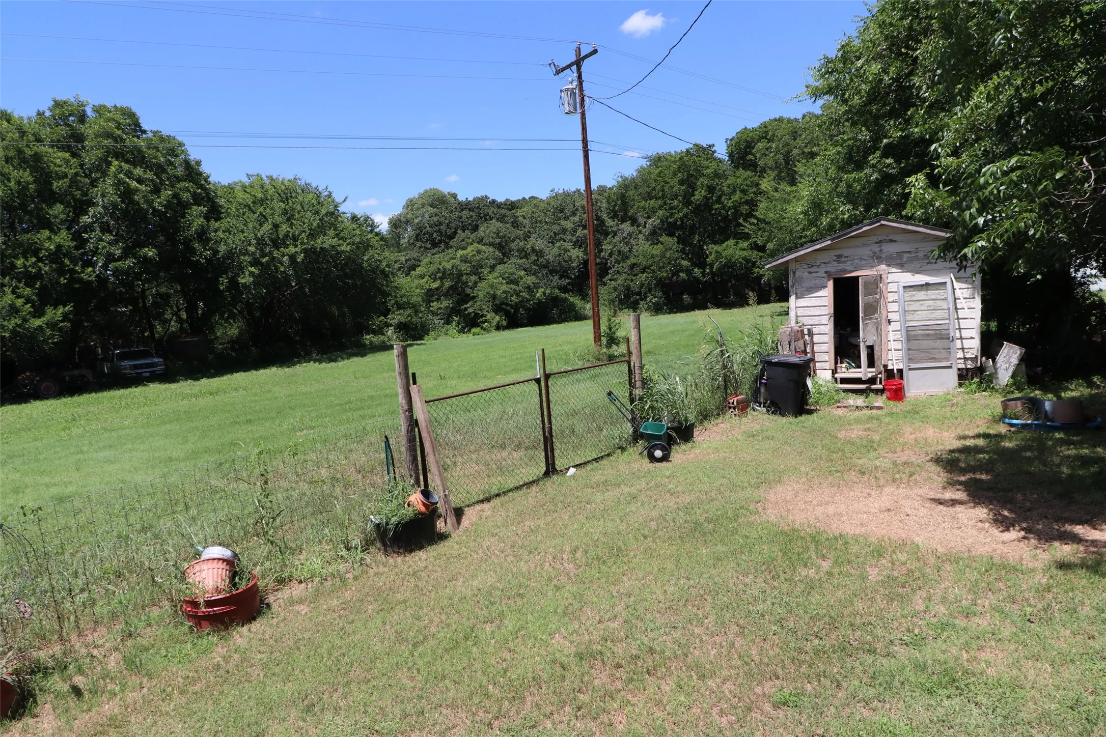 Expansive green space with a wood-sided outbuilding and chain-link fence