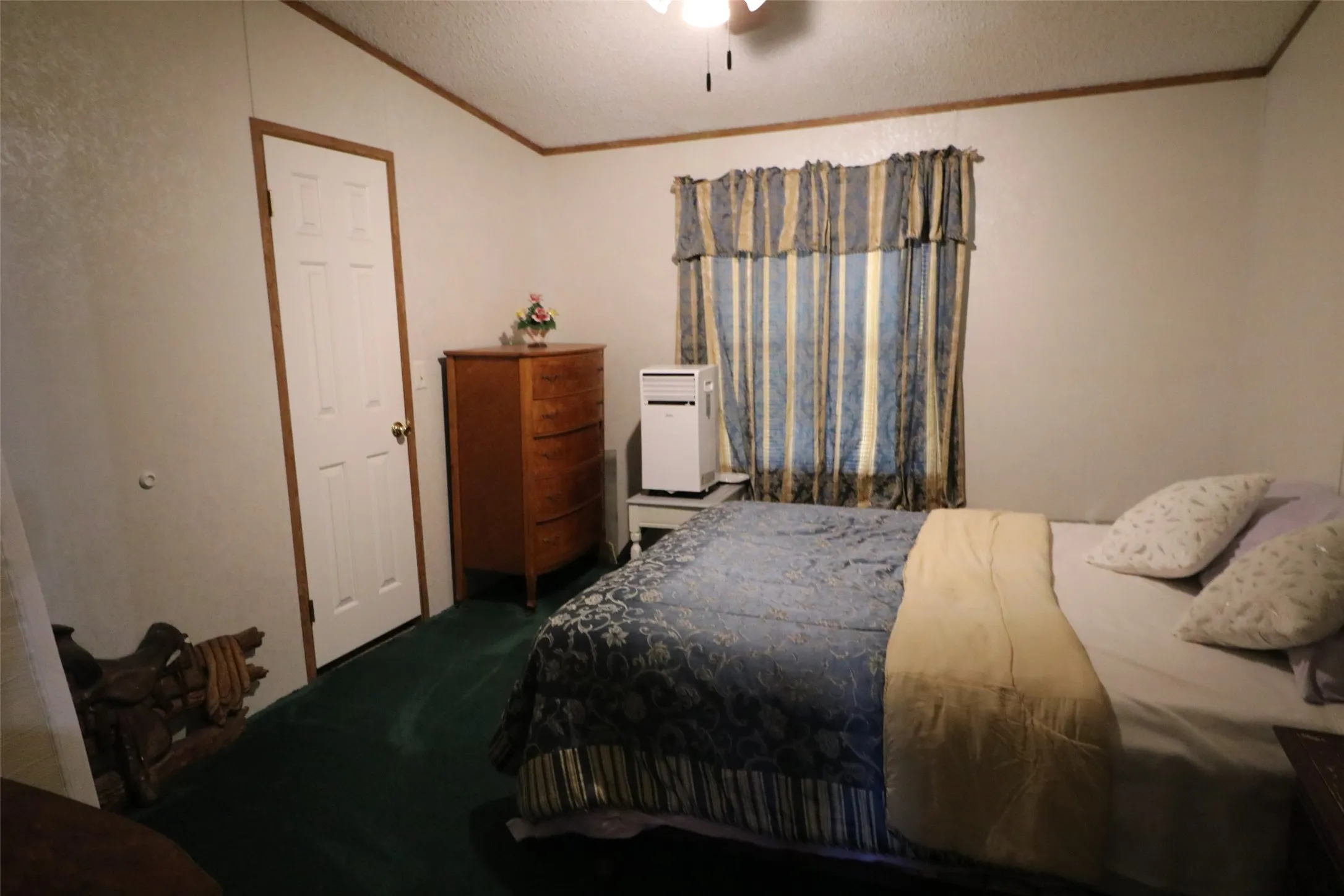 Bedroom with plush green carpeting, white walls, and wood-finish trim
